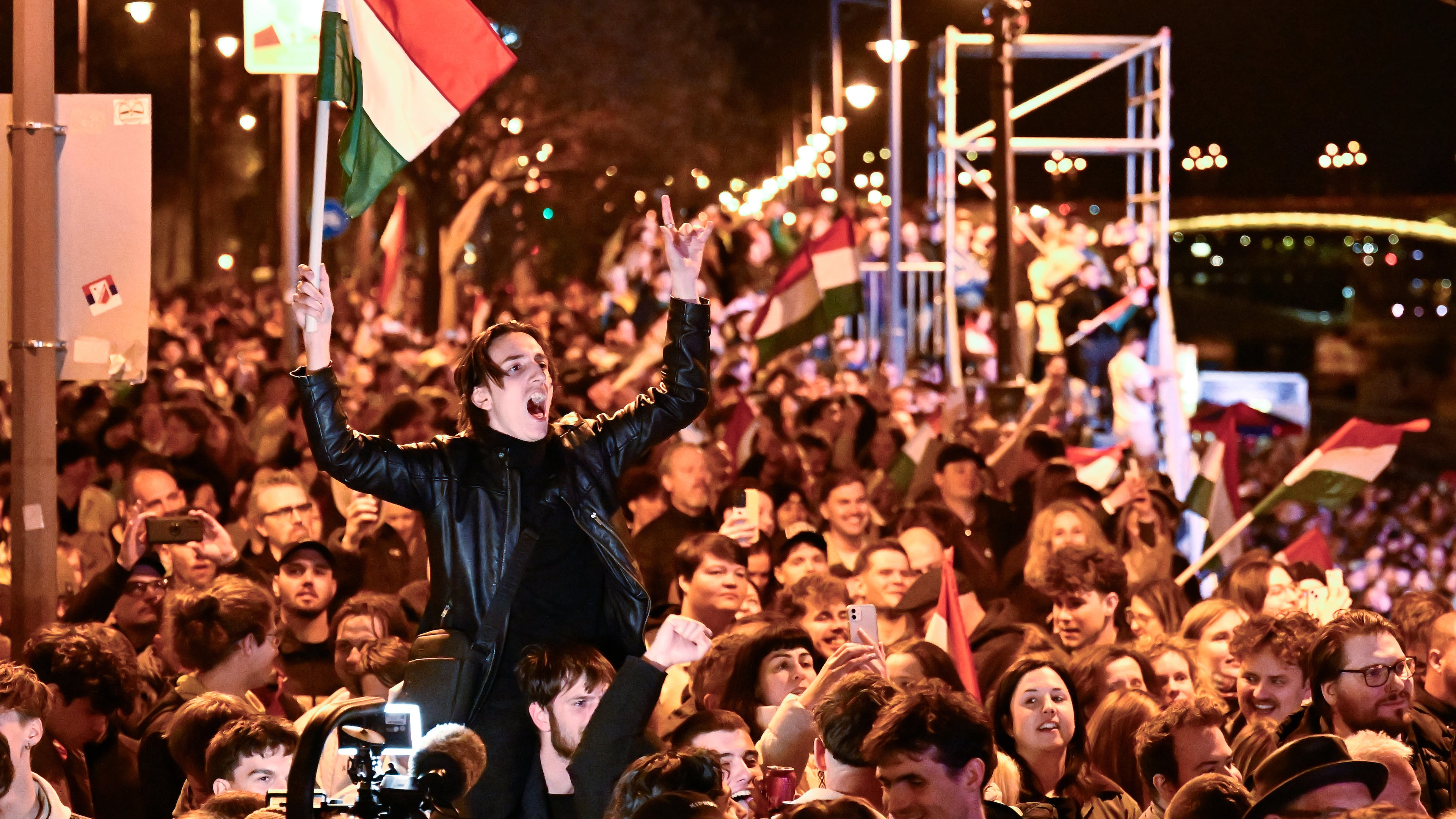 A man waves a Hungarian flag as he celebrates in the streets after the announcement of partial results of the Hungarian parliamentary election in Budapest, Hungary, Sunday, April 12, 2026. (AP Photo/Denes Erdos)