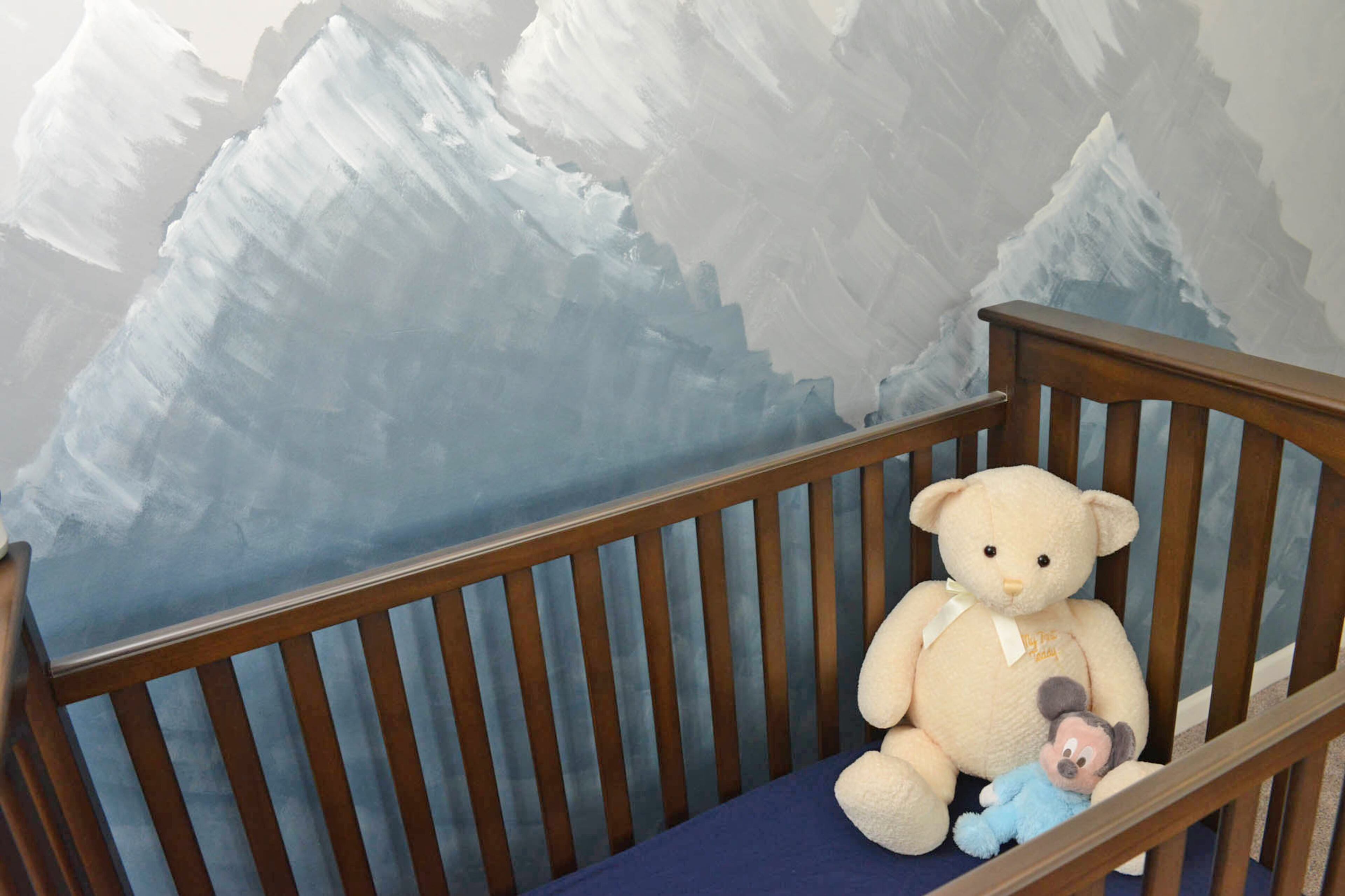A hand-painted range of blue and gray mountains look over the crib. Matthew painted the mural when he and Becky decided on a mountain forest theme for the nursery.