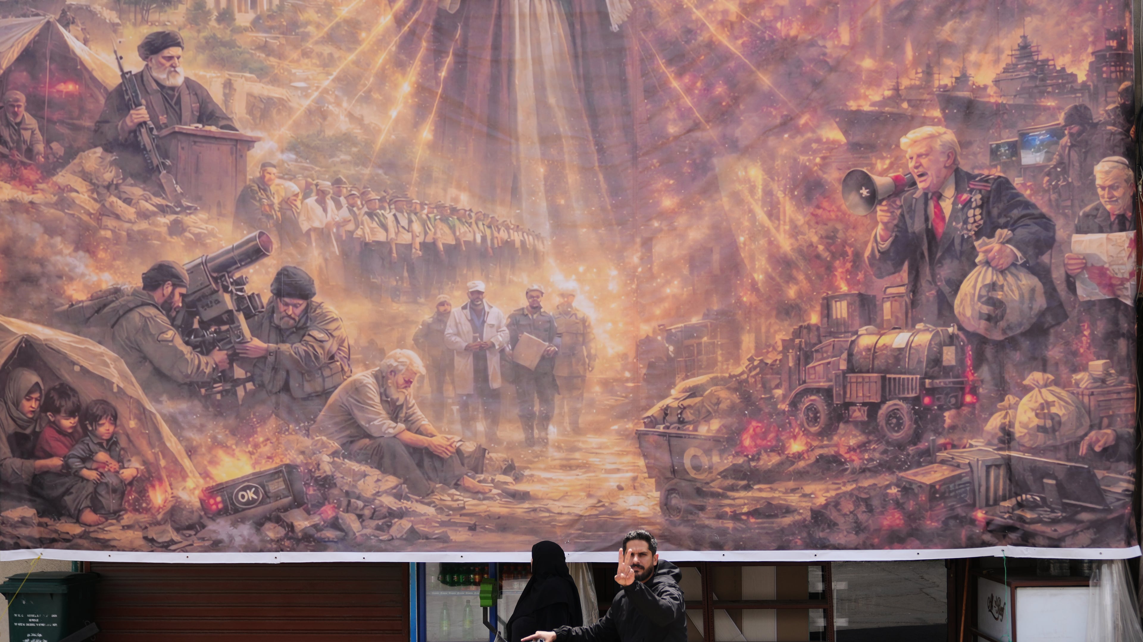 A man on a scooter flashes a victory sign as he drives past a giant portrait depicting the war in the Middle East triggered by the U.S.-Israel strikes on Iran on Feb. 28, in the southern village of Kfar Sir, Lebanon, on Tuesday, April 21, 2026. (AP Photo/Hassan Ammar)