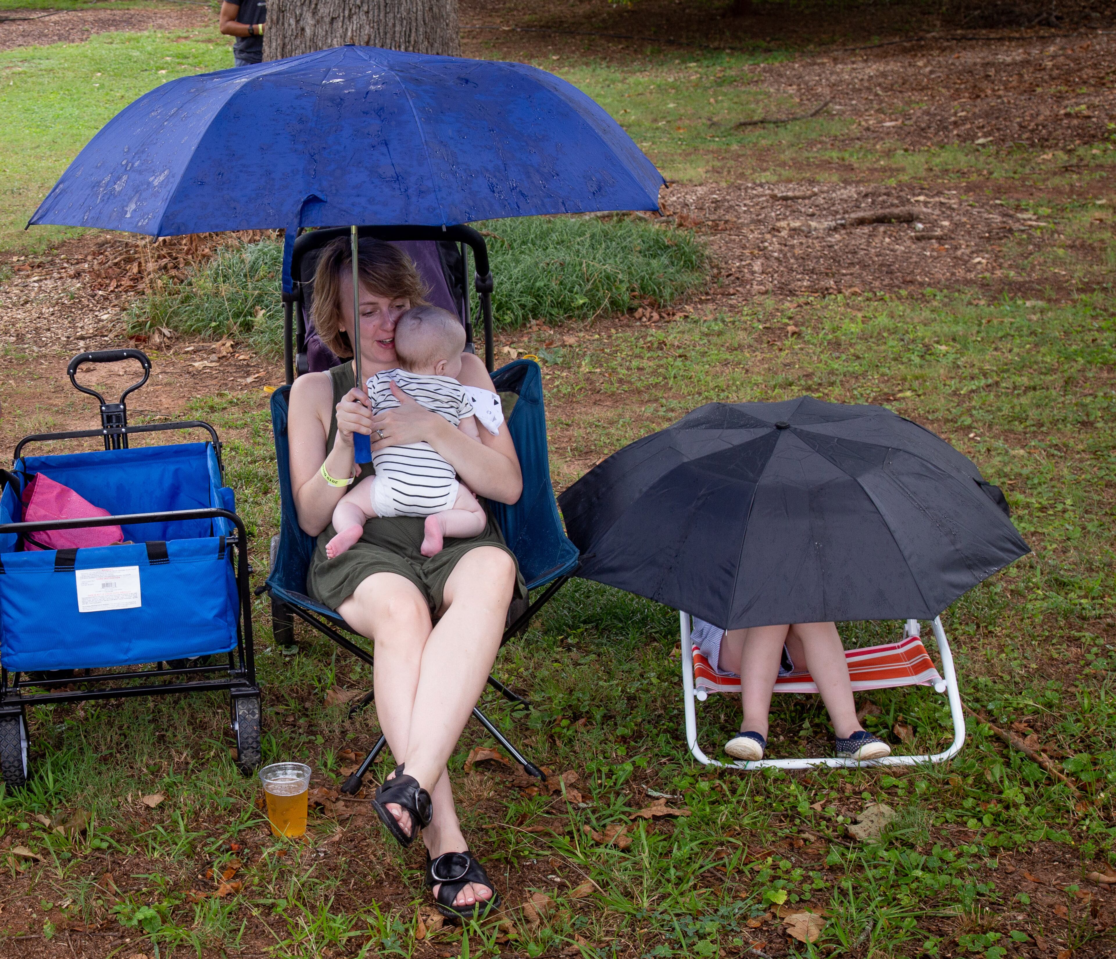 Inga Chismar, her son Lukas and daughter Amelia (R) try to stay dry during a short rain shower at the 19th annual Decatur BBQ Blues & Bluegrass festival on Saturday, August 10, 2019. STEVE SCHAEFER / SPECIAL TO THE AJC