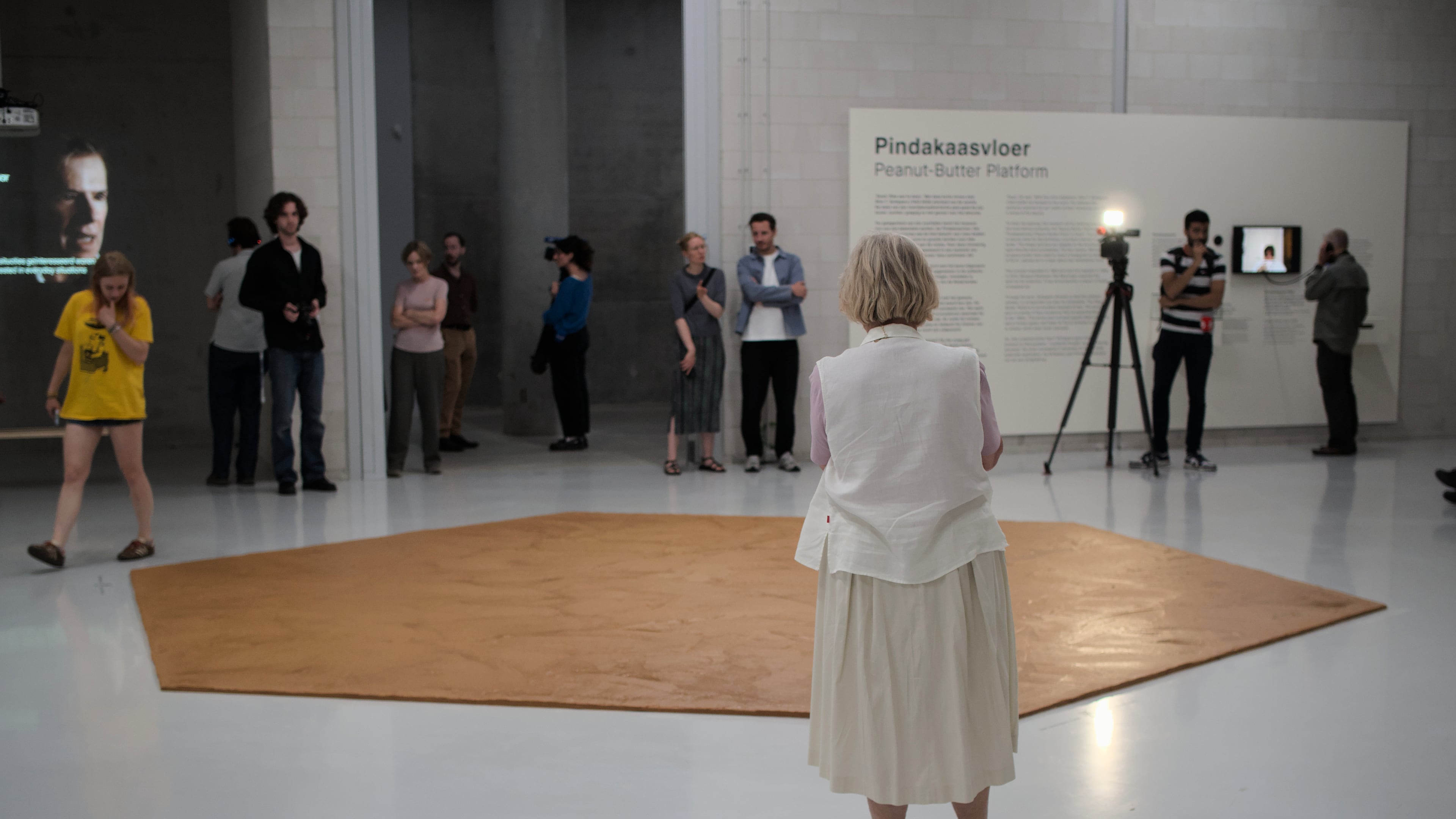 In this photo provided by Niels van der Pas, people look at the peanut butter floor spread across a museum floor in tribute to Dutch artist Wim T. Schippers, who died last month, in Rotterdam, the Netherlands, Thursday, July 9, 2026.(Niels van der Pas/via AP)