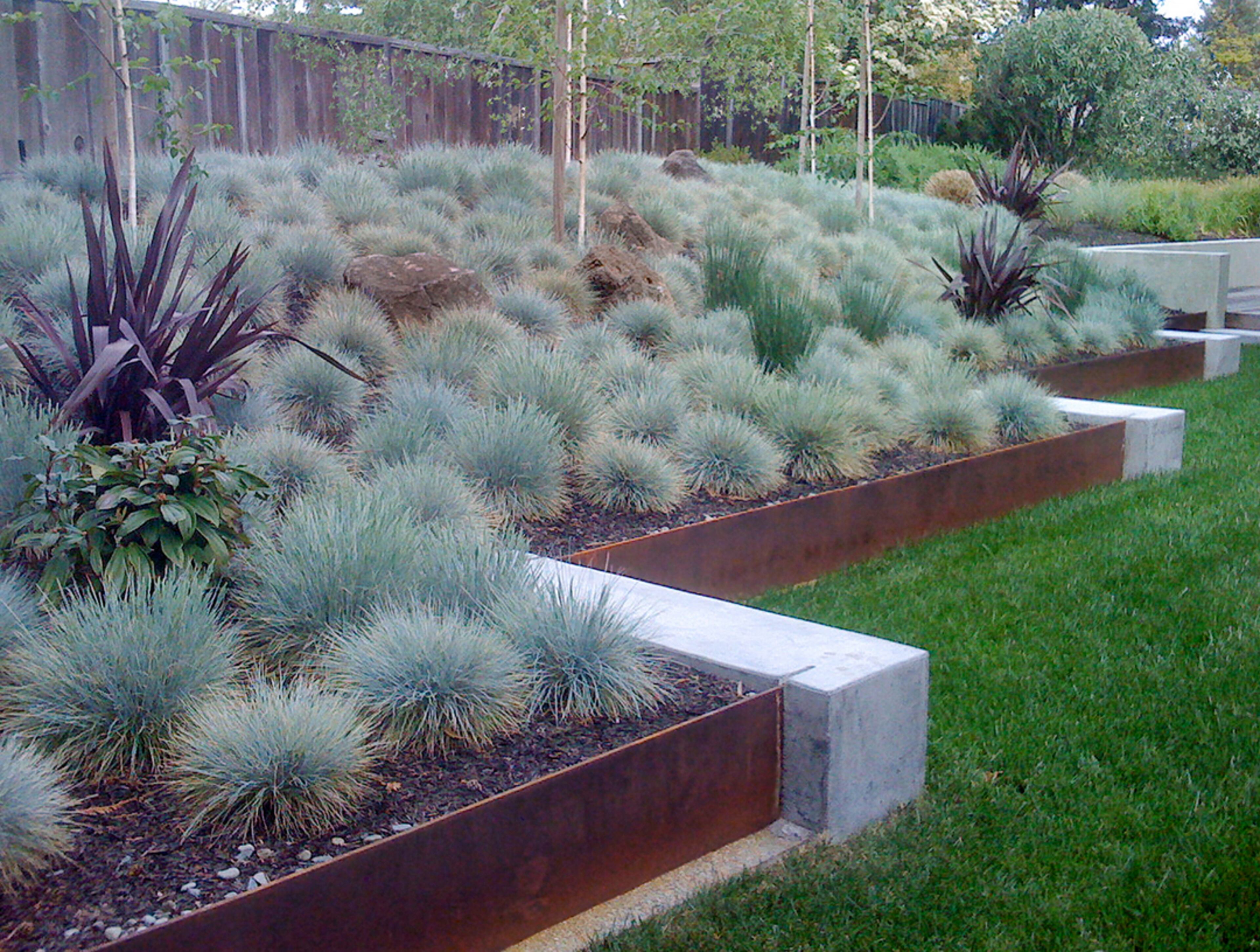 Made of durable Cor-Ten steel, the rusty retaining walls were embedded into smooth concrete seat walls.