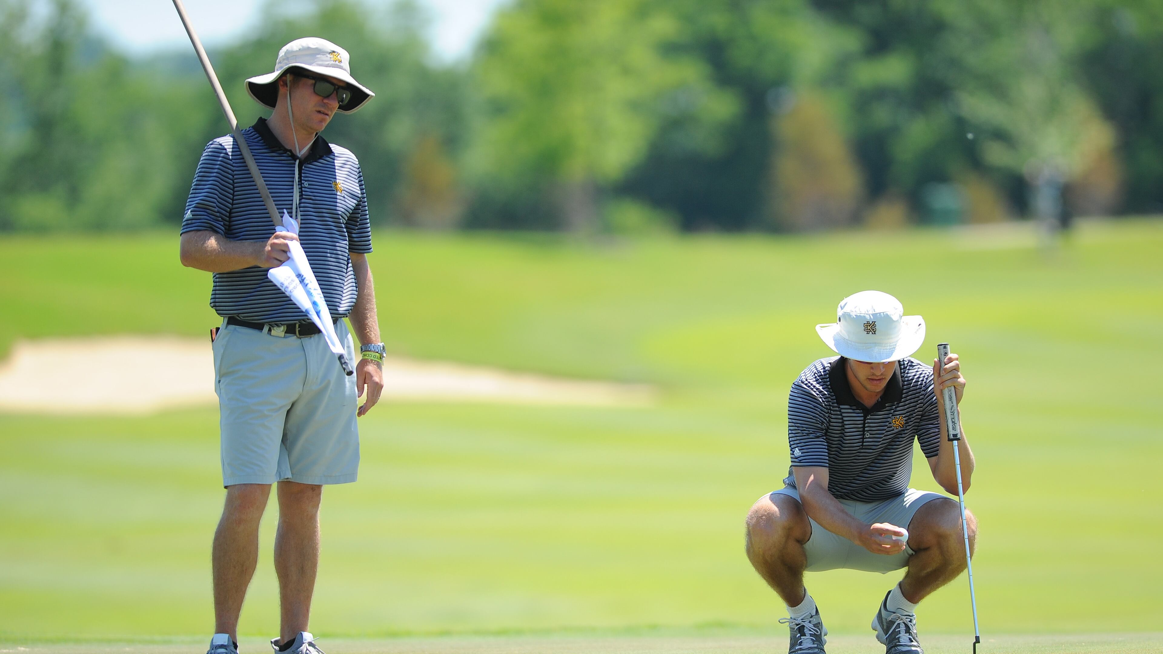 Kennesaw State golf coach Bryant Odom minds the flag while sophomore Jake Fendt considers his putt at the NCAA regional. (Tim Cowie/Kennesaw State)