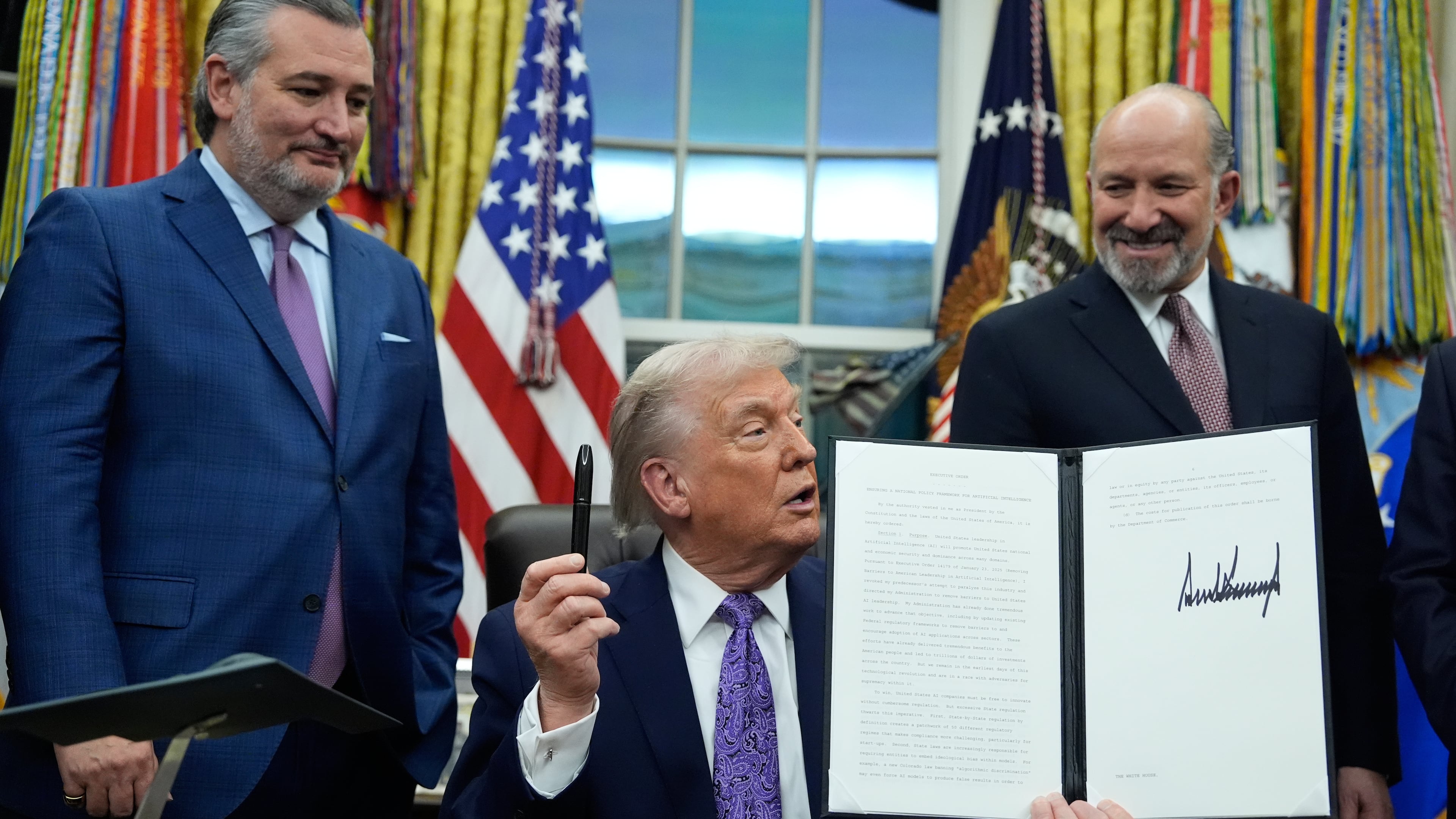 Flanked by Sen. Ted Cruz, R-Texas, left, and Secretary of Commerce Howard Lutnick, President Donald Trump displays his signed AI initiative in the Oval Office of the White House, Thursday, Dec. 11, 2025, in Washington. (Alex Brandon/AP)