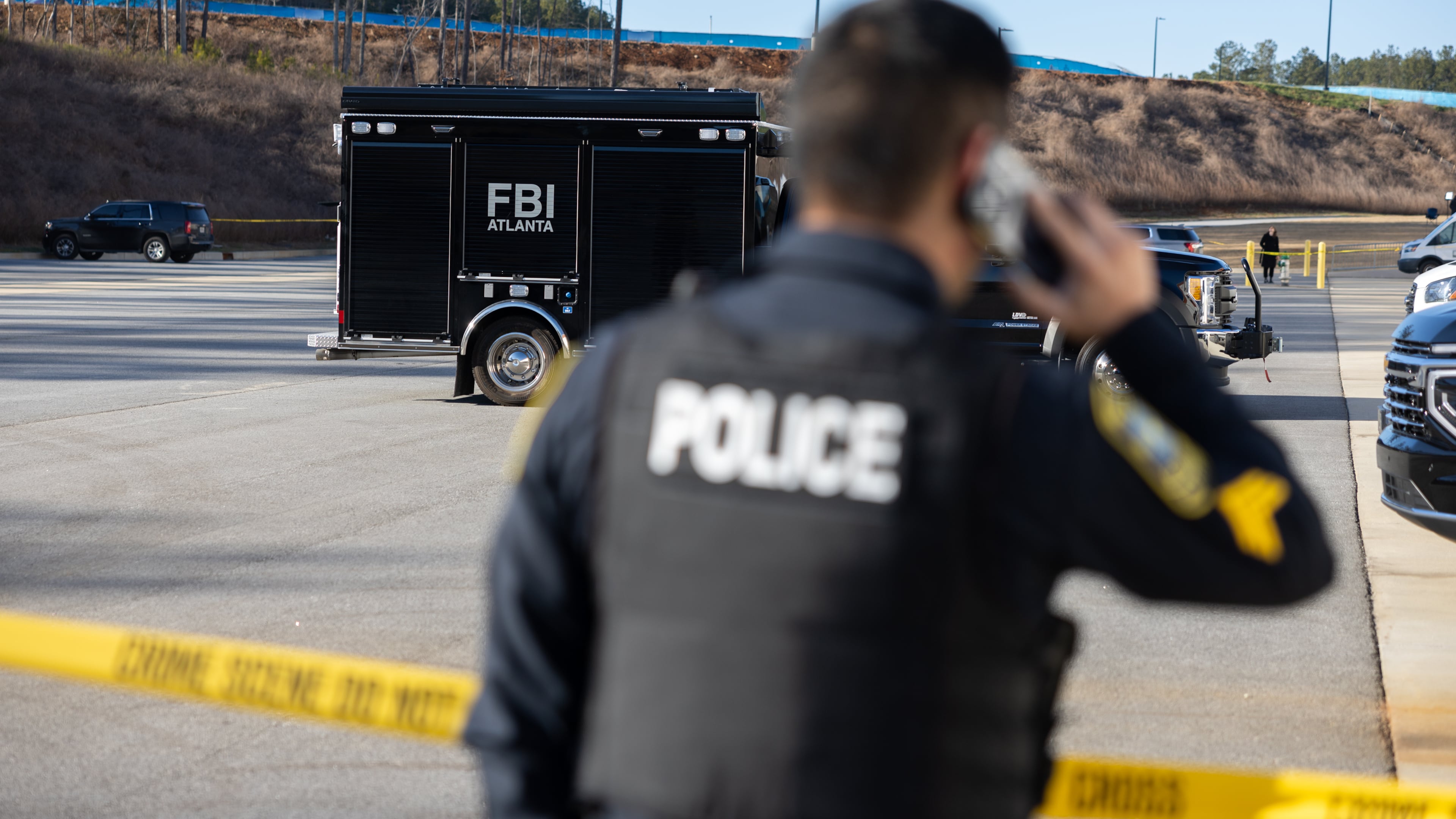 A police officer keeps guard in front of crime scene tape as the FBI conducts a raid on the Fulton County Election Hub and Operation Center in Union City on Wednesday, Jan. 28, 2026. (Arvin Temkar/AJC)