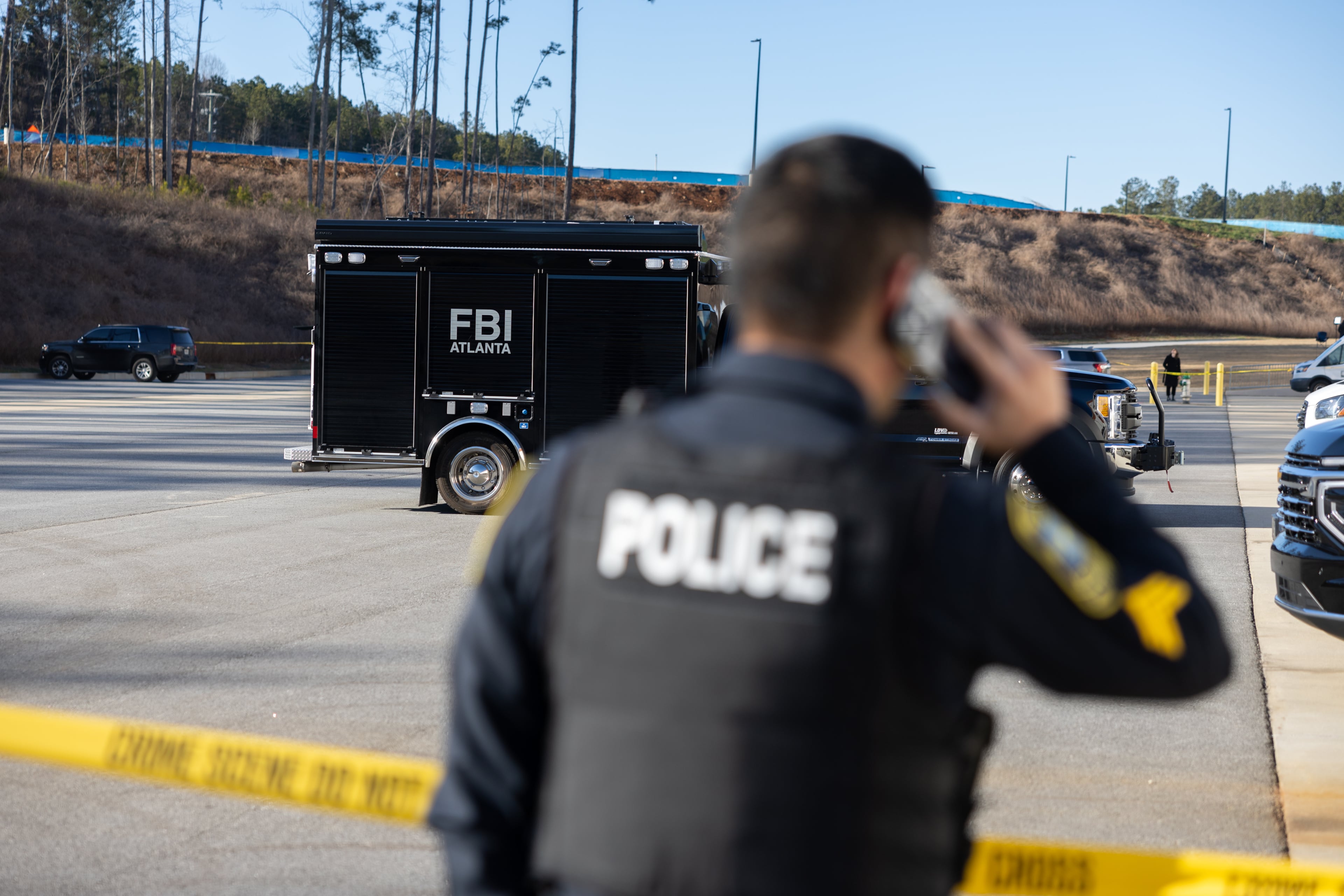 A police officer kept guard in front of crime scene tape as the FBI conducted a raid on the Fulton County Election Hub and Operation Center in Union City last week. (Arvin Temkar/AJC)