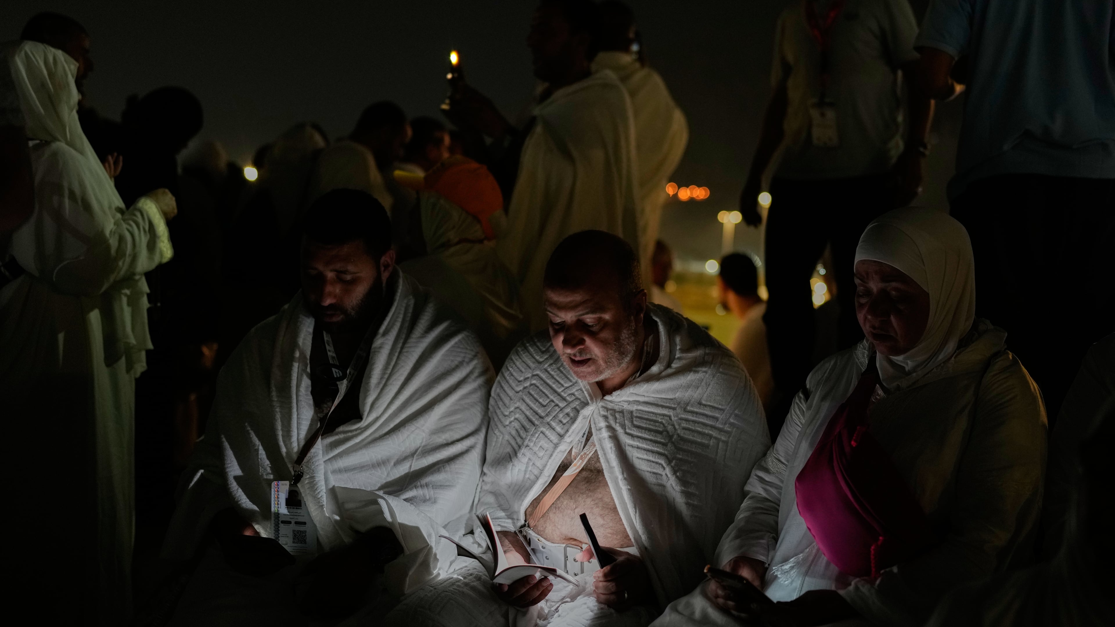Muslim pilgrims read a copy of Islam's holy book Quran atop of the rocky hill known as the Mountain of Mercy, on the Plain of Arafat, during the annual Hajj pilgrimage near the holy city of Mecca, Saudi Arabia, Tuesday, May 26, 2026. (AP Photo/Altaf Qadri)