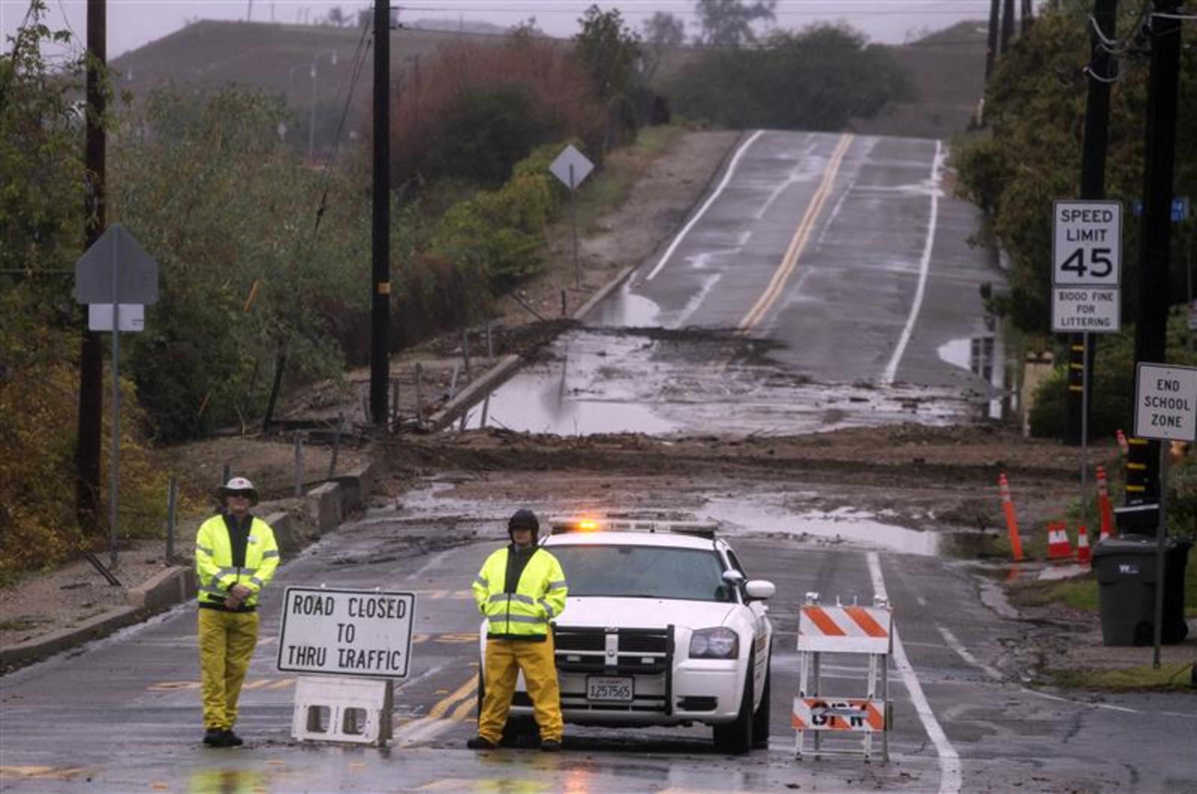 Police officers block a section of a road after mud and debris had blocked the thoroughfare along hillside in Glendora, Calif., Friday, Feb. 28, 2014. The first wave of a powerful Pacific storm spread rain and snow early Friday through much of California, where communities endangered by a wildfire just weeks ago now faced the threat of mud and debris flows. (AP Photo/Ringo H.W. Chiu)