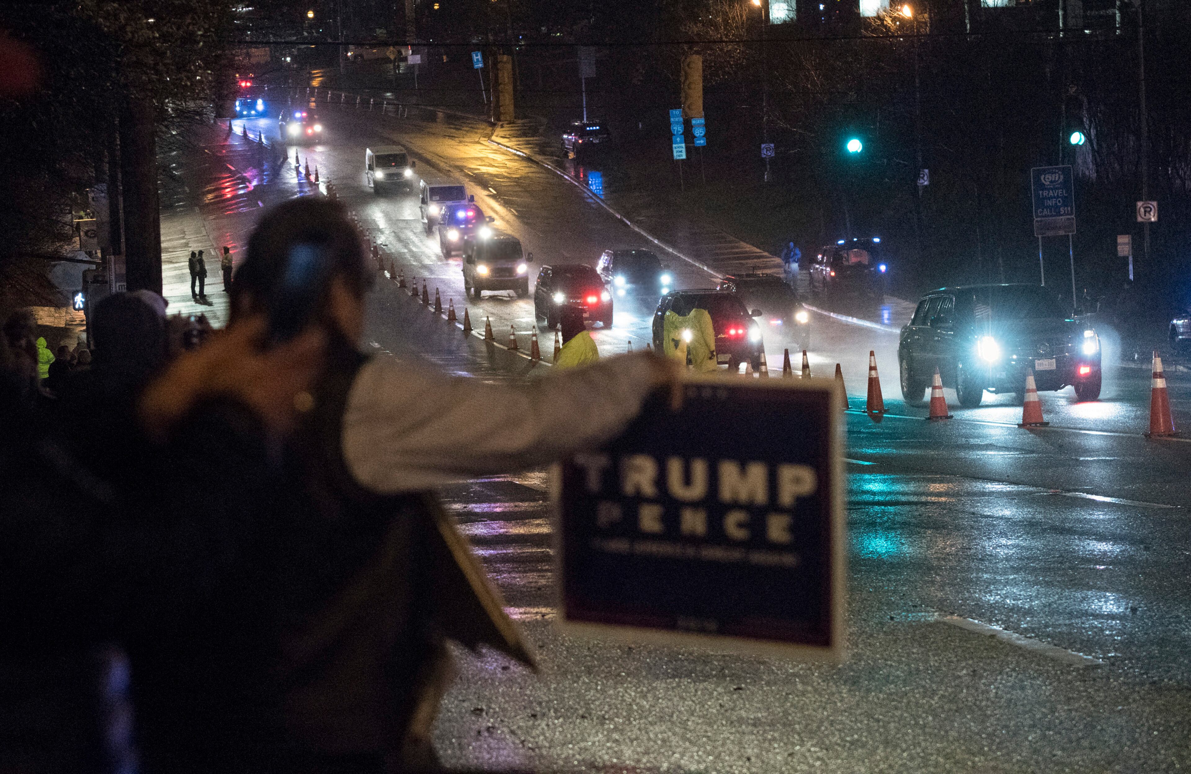 Iranian American Nasser Jamali, of Chamblee, holds up a sign as the Presidential motorcade passes him on Northside Drive before entering for the College Football National Championship game held at Mercedes-Benz Stadium on Monday Jan. 8, 2018, in Atlanta. Jamali joined other Iranian Americans in demonstrating support for the President.(John Amis)