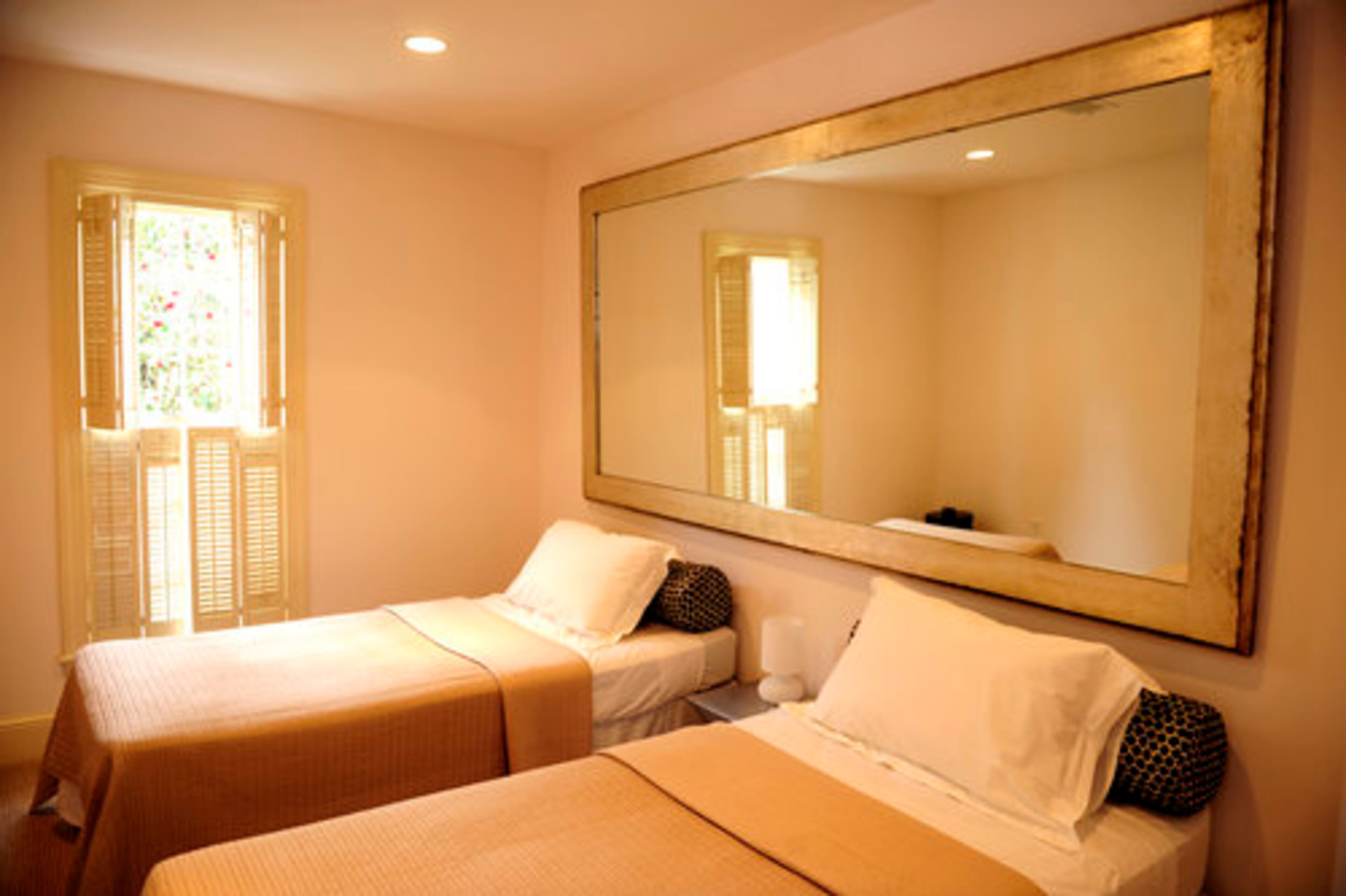 The bedroom in the ground floor apartment has a modern cottage-like feel. The muted tones get just the right kick with the modern patterns in the bolsters.