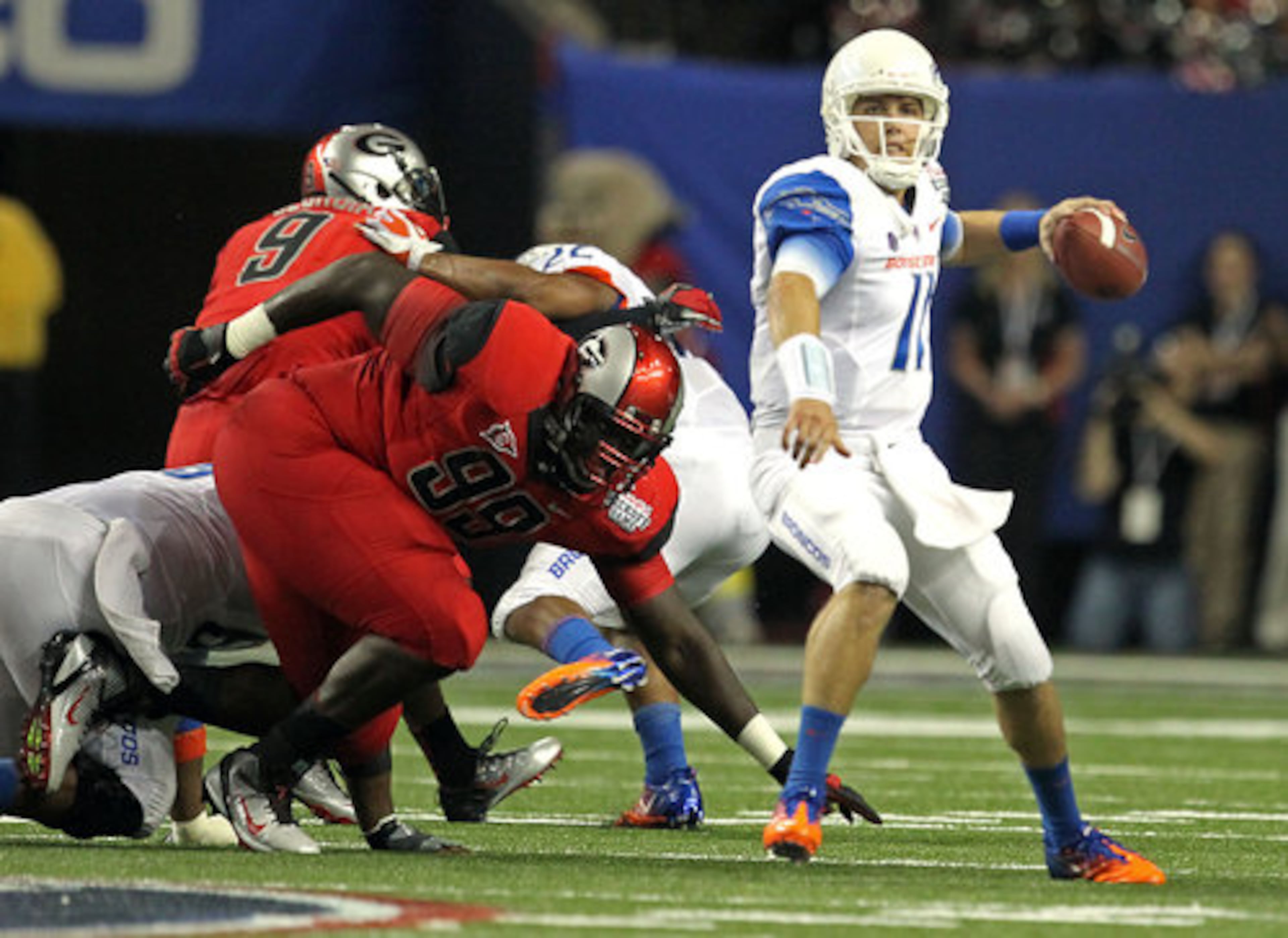 Boise State quarterback Kellen Moore, right, looks to pass as he gets away from the defensive pressure by Georgia nose tackle Kwame Geathers (99).