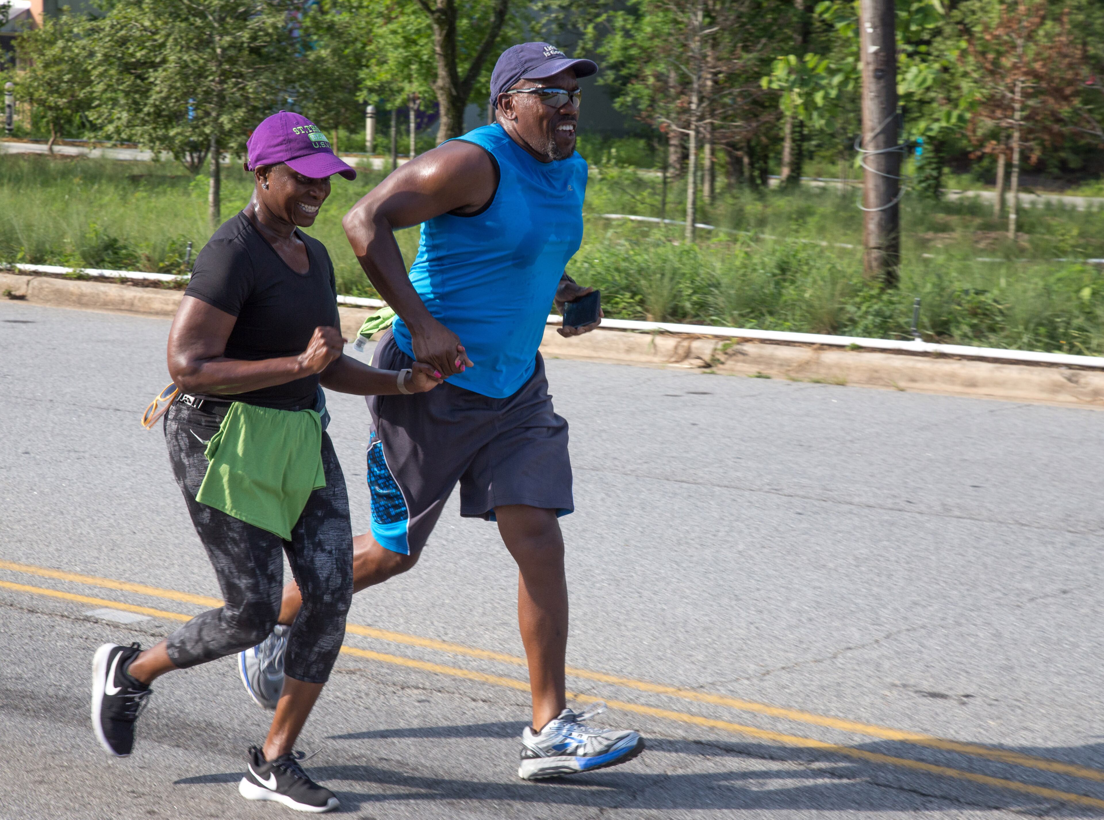 Davon Sharp (L) and Phillip Davenport hold hands while crossing the finish line during the Reggae 5K Fun Run near Gordon-White Park in the West End Neighborhood Saturday, July 7, 2018. STEVE SCHAEFER / SPECIAL TO THE AJC