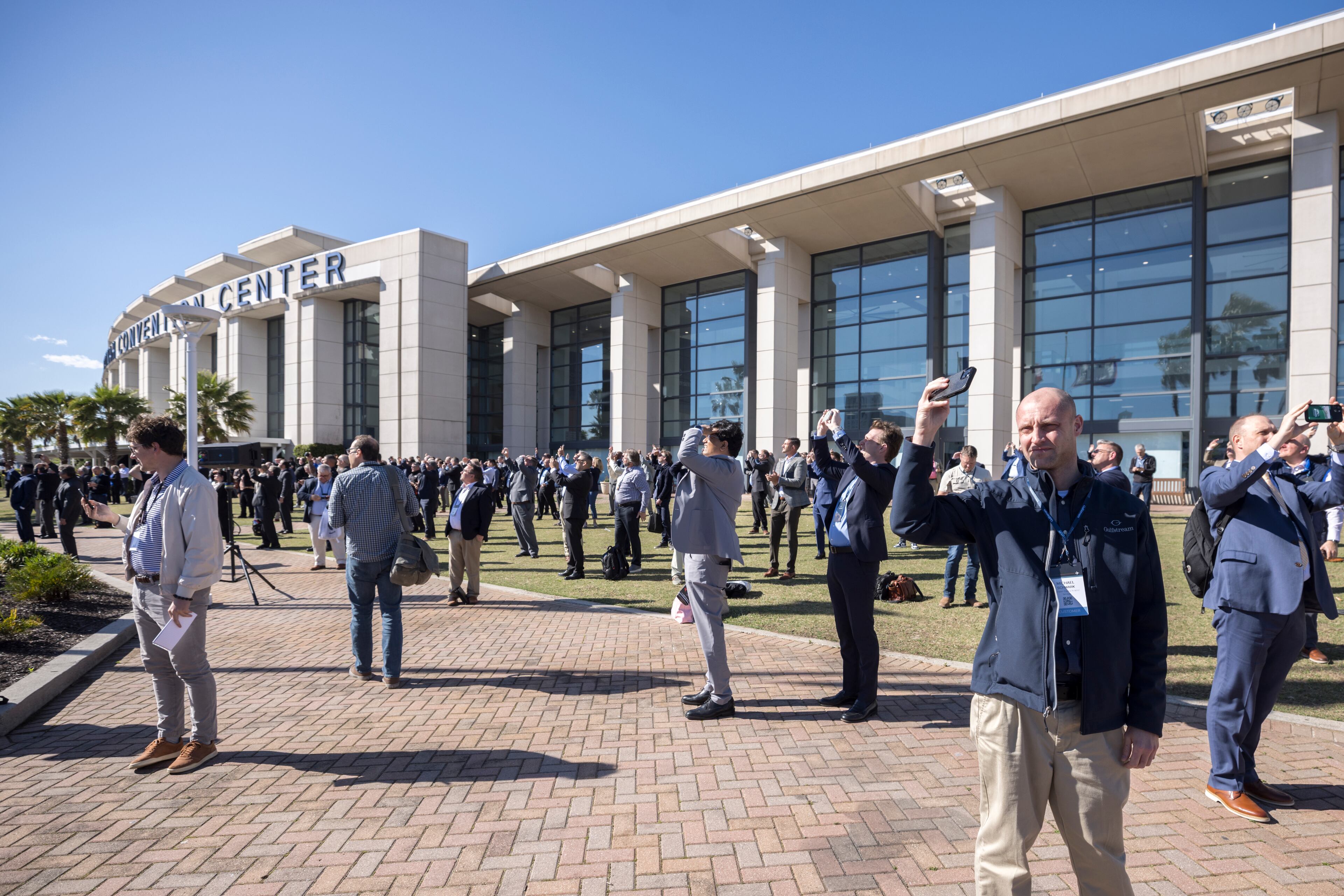 SAVANNAH, GA - APRIL 04, 2024: A group of people watch the G700 and G800 perform a fly-over during an event to celebrate the newly certified Gulfstream Aerospace Corporation G700, Thursday, April 4, 2024, in Savannah, Ga. The clearance of the G700 from the FAA paves the way for Gulfstream to start delivering the jet to customers who have placed orders. (AJC Photo/Stephen B. Morton)