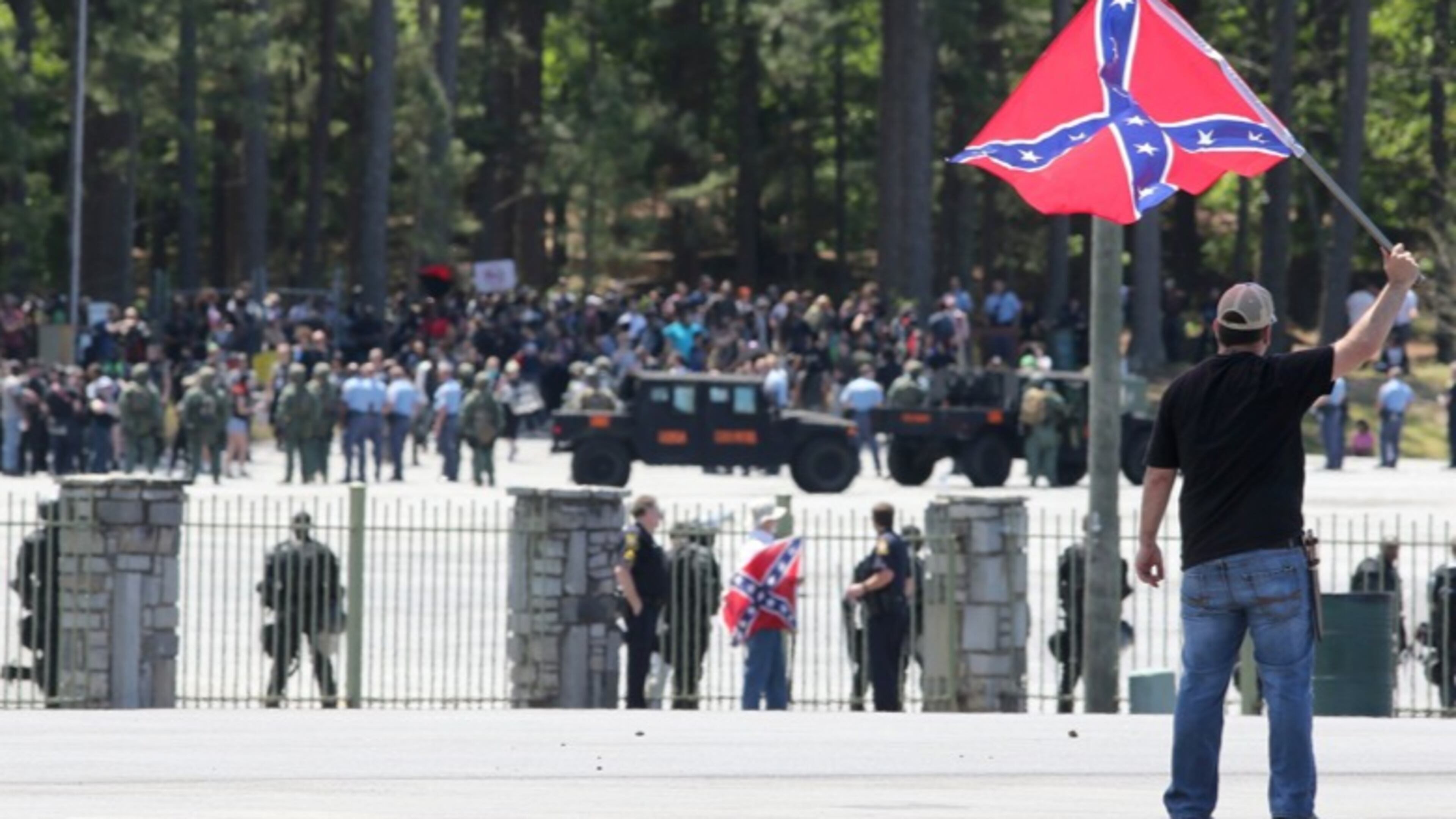 Joseph Andrews, one of a small group with the Rock Stone Mountain rally, waves a confederate battle flag towards a mass of counter-protesters more than 100 yards away at Stone Mountain Park on Saturday afternoon April 23, 2016 where a white power protest and two counter protests were scheduled.