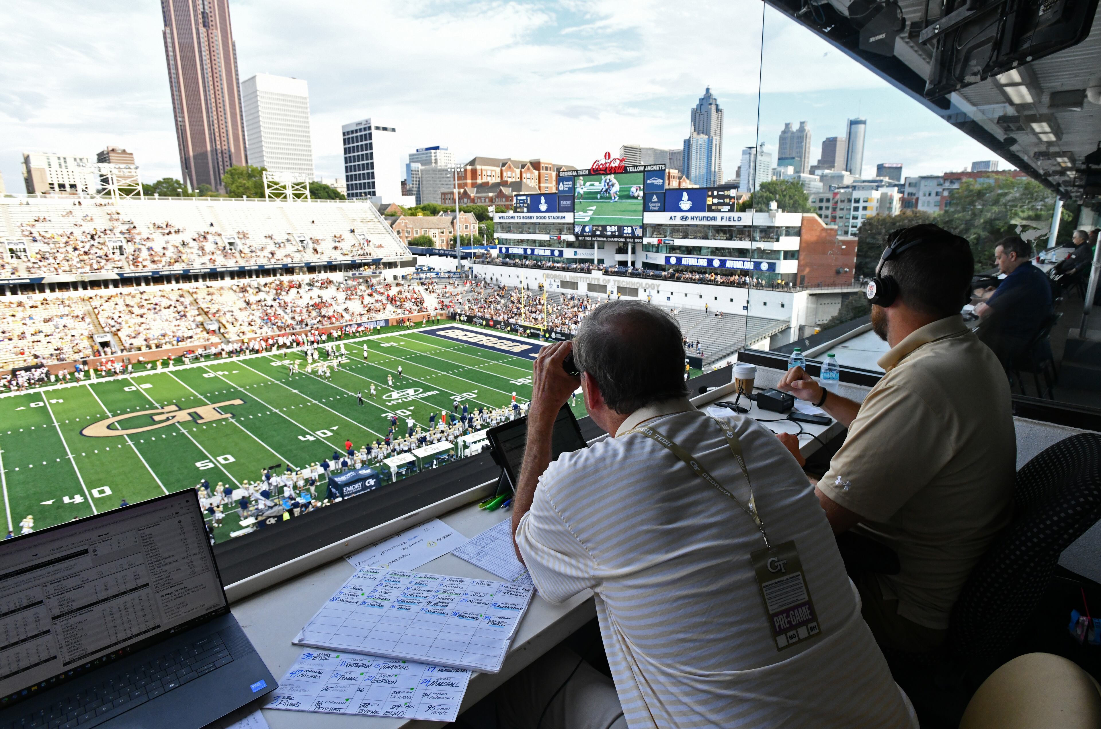 Al Ciraldo Jr. uses binoculars to look as he sits next to Analyst Andrew Gardner during an NCAA college football game at Georgia Tech's Bobby Dodd Stadium, Saturday, September 6, 2025, in Atlanta. Georgia Tech won 59-12 over Gardner-Webb. (Hyosub Shin / AJC)