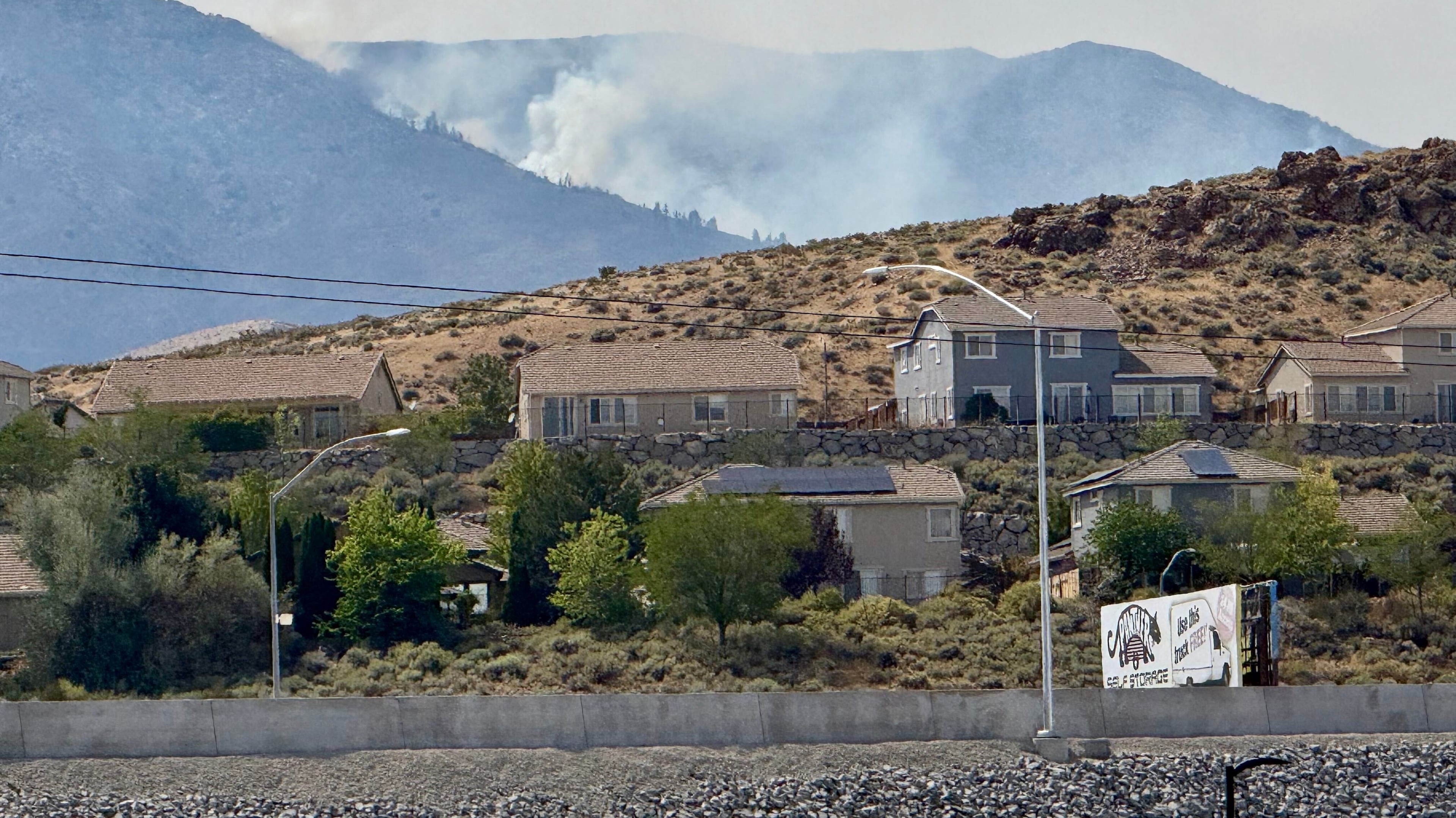 Smoke billows in the distance as a wildfire burns in Reno, Nev., Sunday, August 23, 2026. (AP Photo/Haven Daley)