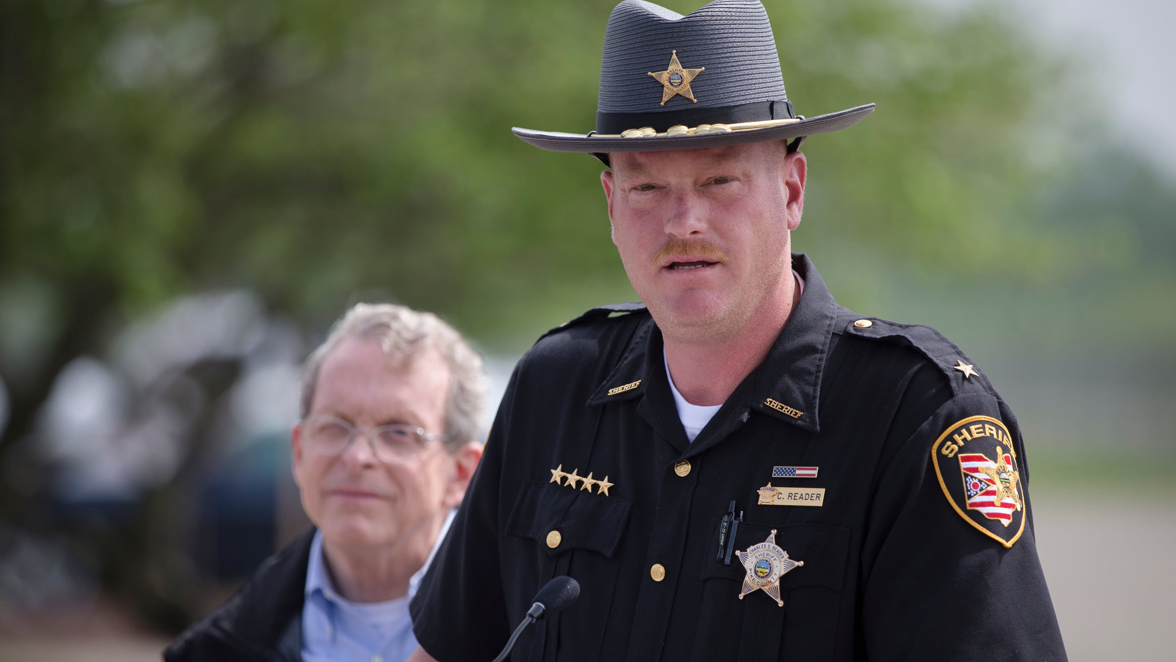 Pike County Sheriff Charles Reader speaks to the media alongside Ohio State Attorney General Mike DeWine during a news conference, Wednesday, April 27, 2016, in Waverly, Ohio. A coroner’s report released Tuesday showed new details of vicious violence in the shooting deaths of eight members of a rural southern Ohio family, finding most victims were shot three to nine times each and some of them were bruised. Meanwhile, the hunt for whoever is responsible continued to expand, with more than 200 law enforcement officials involved. (AP Photo/John Minchillo)
