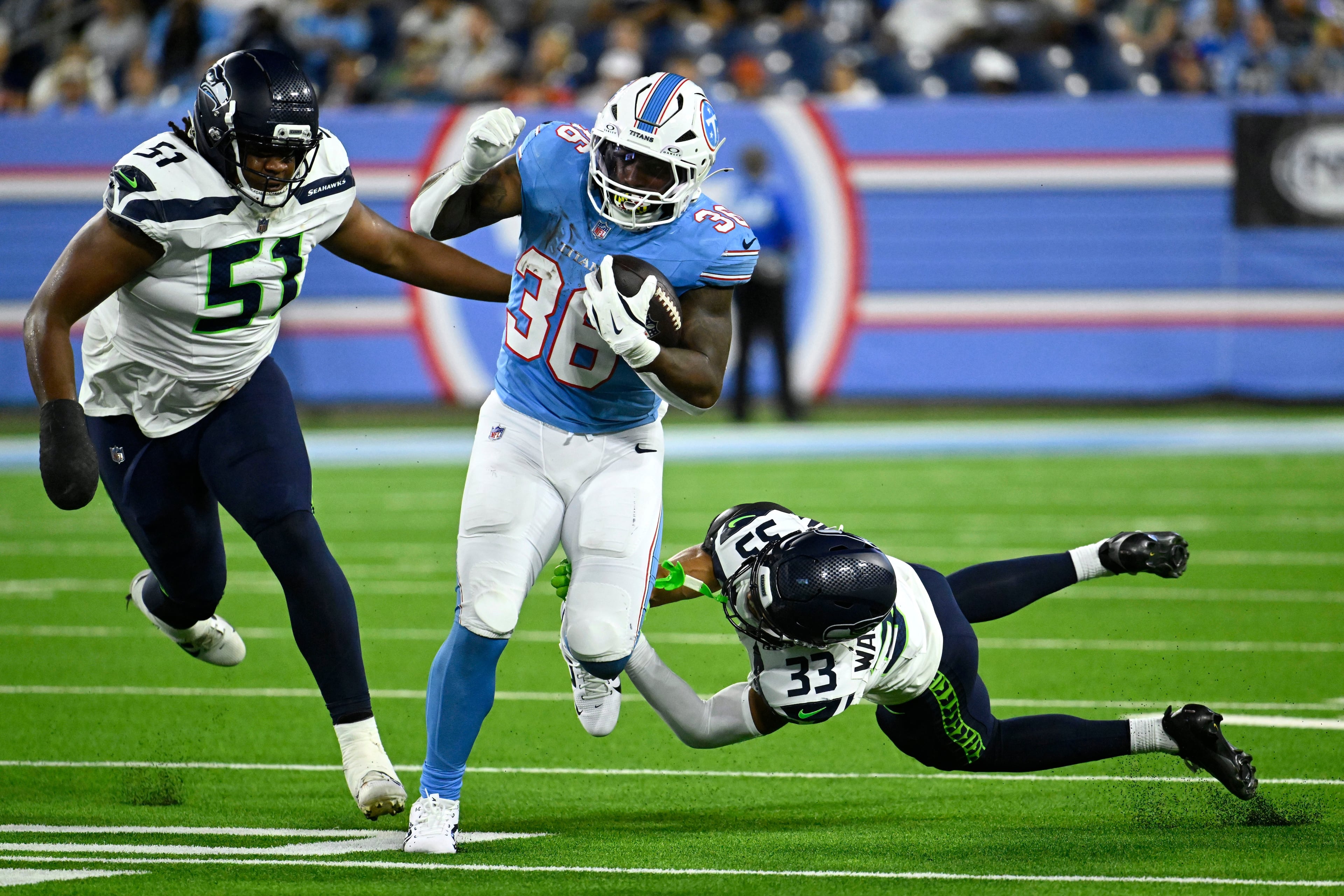 Titans running back Julius Chestnut (center) runs from then-Seahawks linebacker Jared Ivey (left) and cornerback Jordan Washington on Sunday, Aug. 23, 2026, in Nashville, Tenn. Seattle waived Ivey on Aug. 30, the final day of roster cuts. (John Amis/AP)