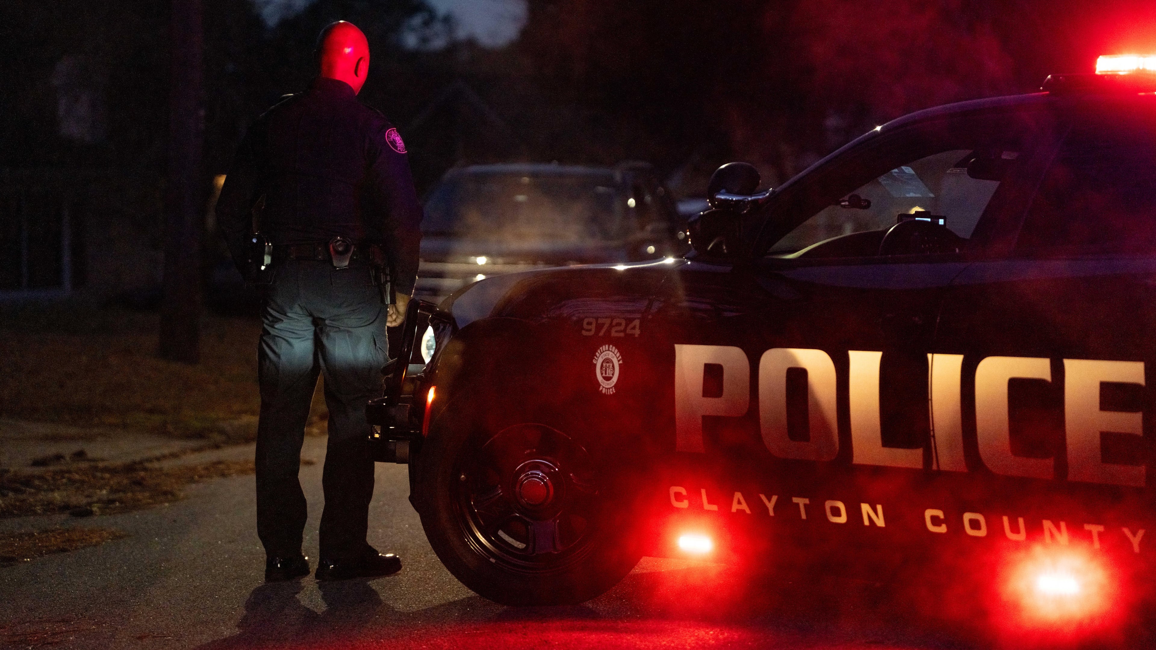 After an officer was shot and a suspect injured during a SWAT standoff, a Clayton County police officer blocks off a section of Summer Chase Drive early Wednesday.