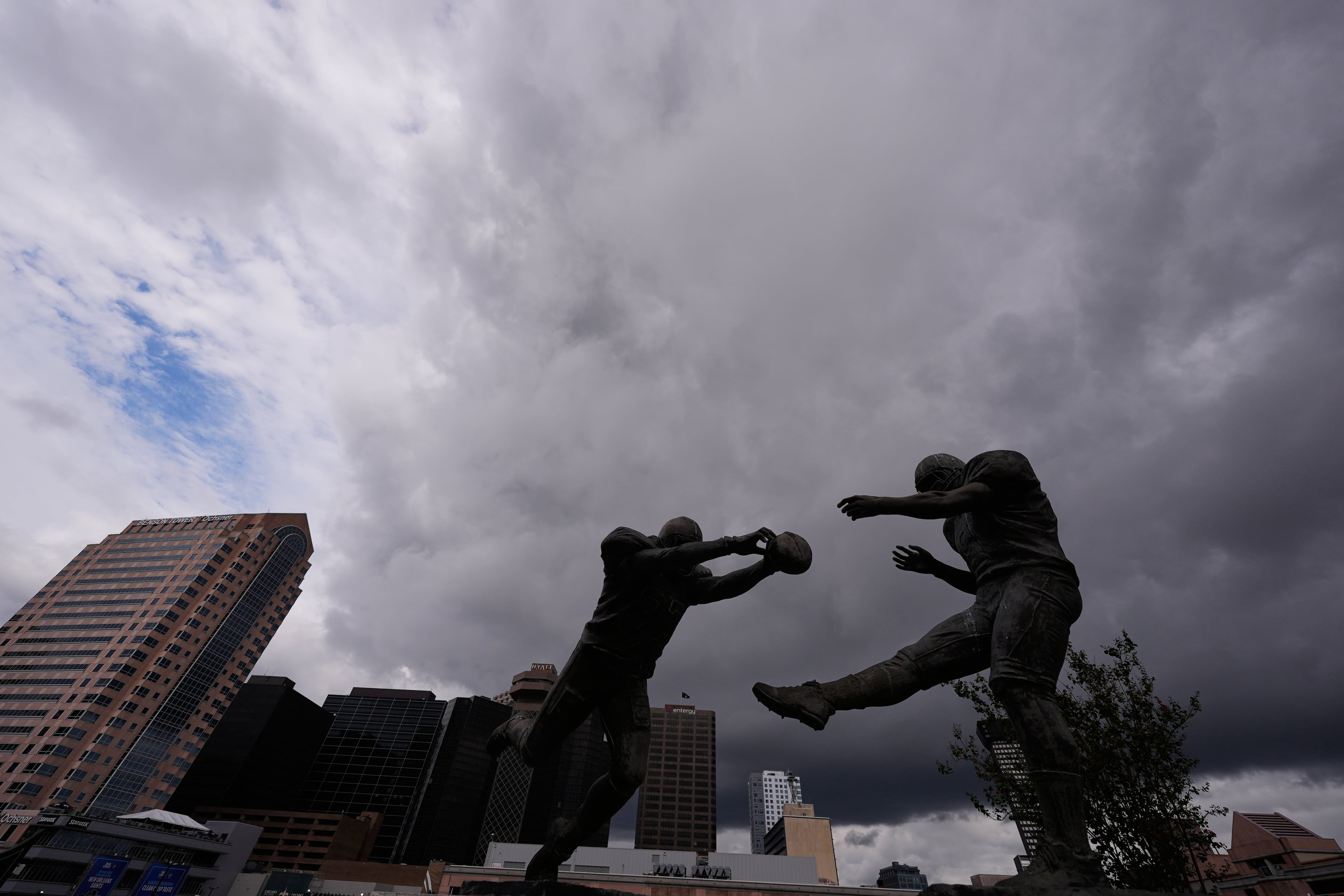 The Rebirth Statue is seen with storm clouds and skyline outside the Superdome, before an NFL football game 20 years later between the New Orleans Saints and the Atlanta Falcons, in New Orleans, Monday, Oct. 5, 2026. The statue features New Orleans Saints' Steve Gleason blocking a punt by Atlanta Falcons punter Michael Koenen, in the first Saints home game after Hurricane Katrina. (Gerald Herbert/AP)