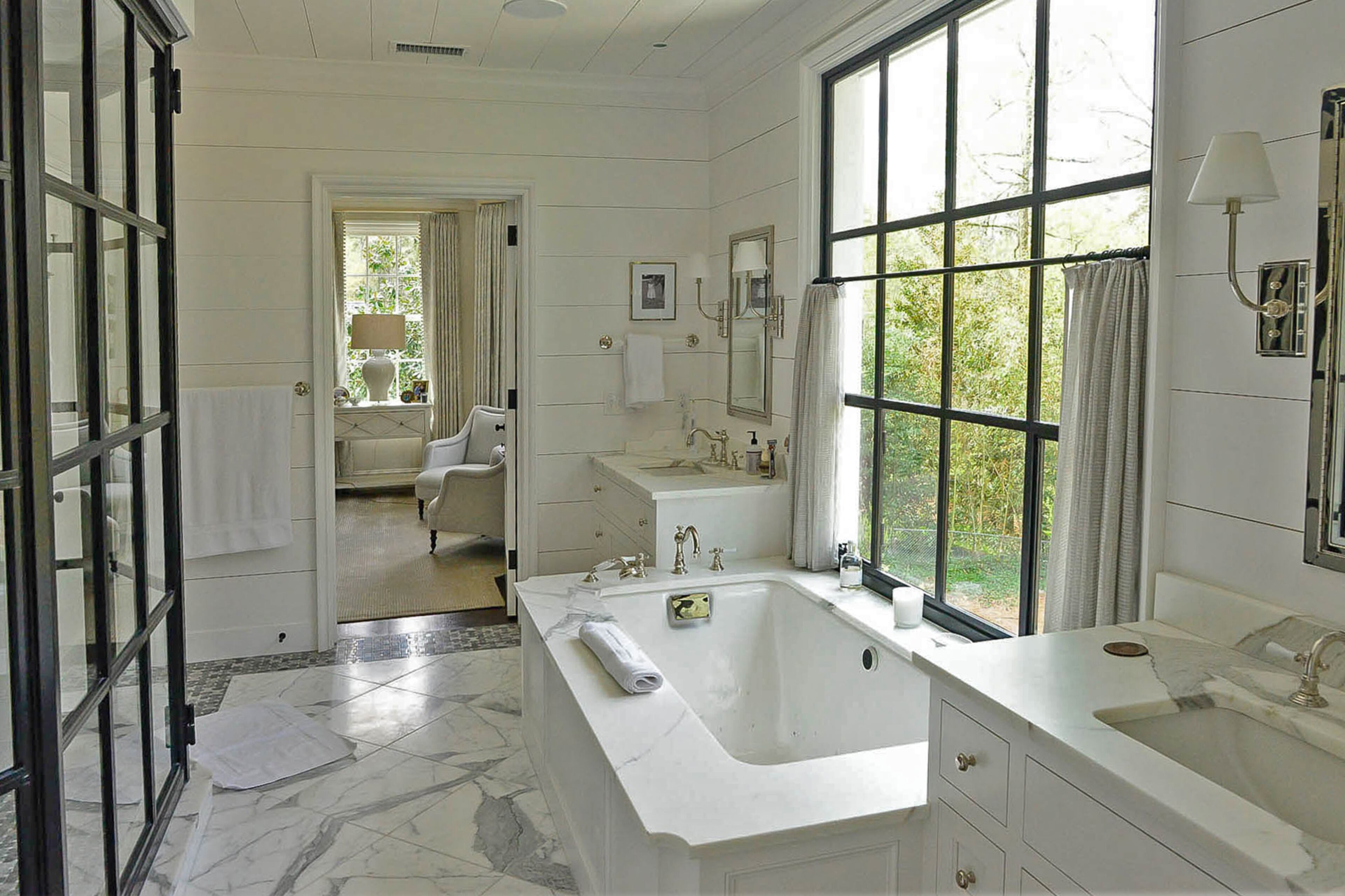 The iron shower enclosure is an alternative to frameless glass doors. The ironwork matches the windows above the tub in the marble master bathroom.