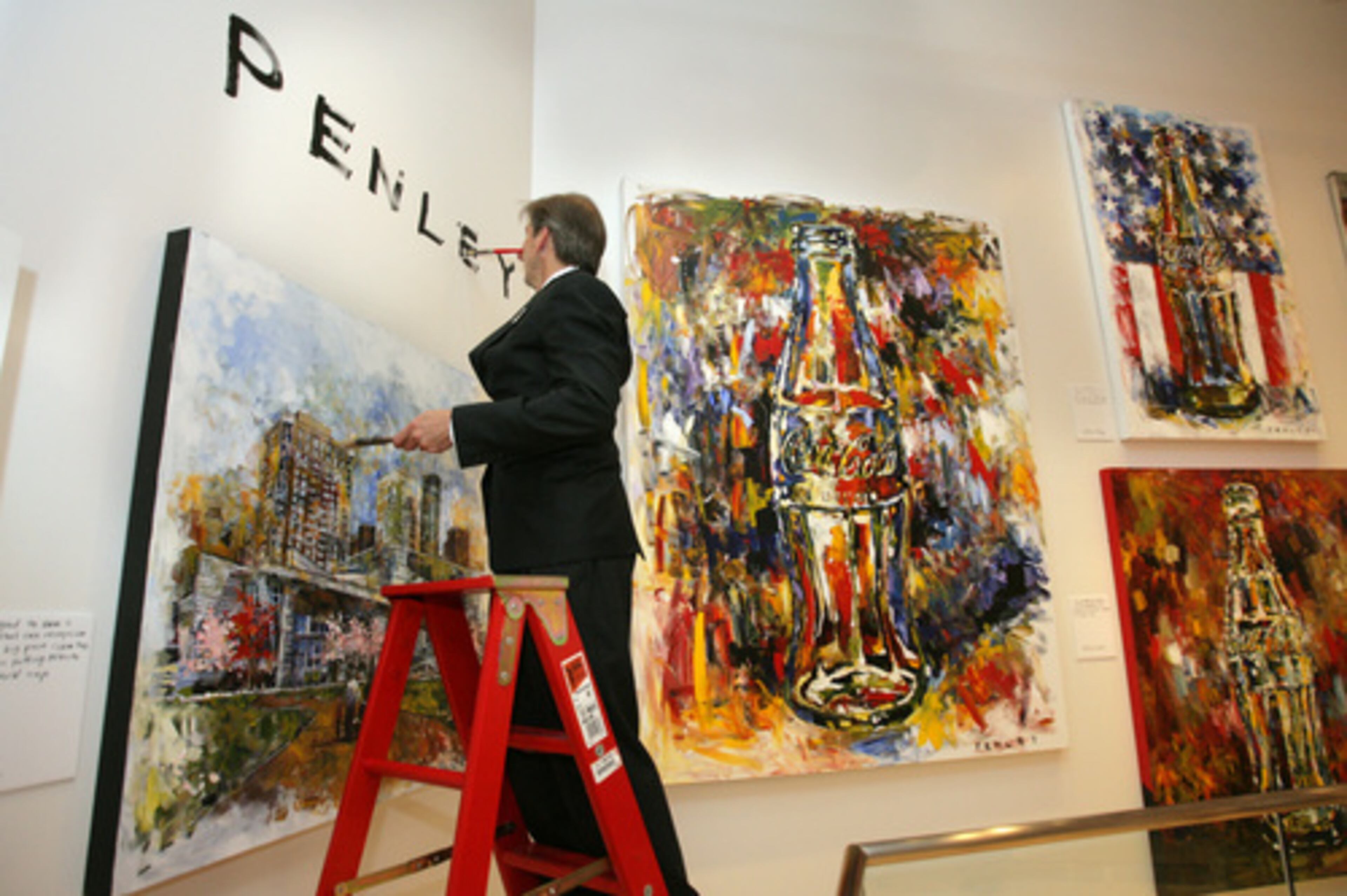Artist Steve Penley signs his name to the wall during his opening in Atlanta's World of Coca-Cola on Thursday. His show will be up for a year, replacing the Andy Warhol exhibit that was on display during the first year of the museum's existence.