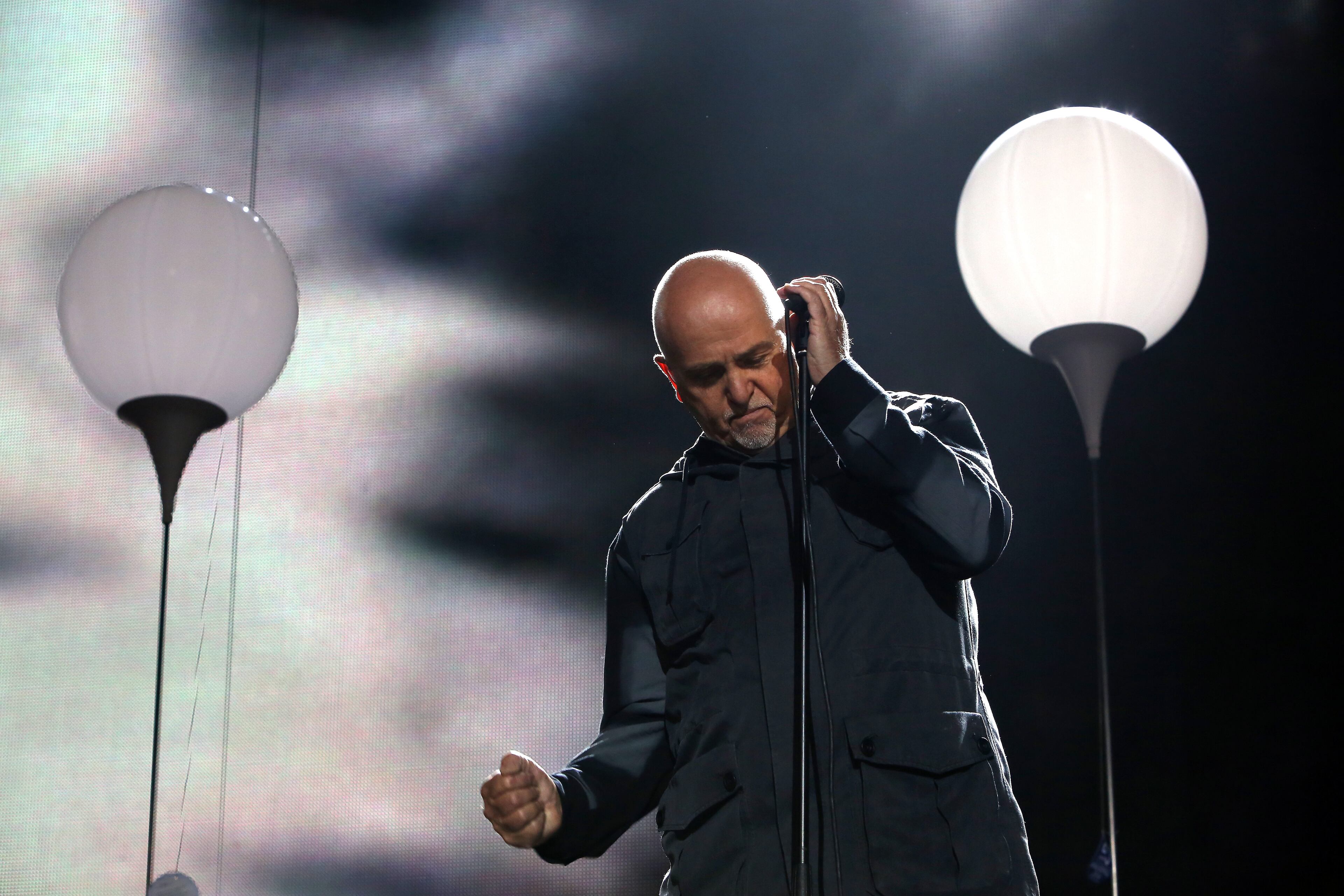 Musician Peter Gabriel performs at the Brandenburg Gate next to a section of the Lichtgrenze light installation during celebrations for the 25th anniversary of the fall of the Berlin Wall on November 9, 2014 in Berlin, Germany. The city of Berlin is commemorating the 25th anniversary of the fall of the Berlin Wall from November 7-9 with an installation of 6,800 lamps coupled with illuminated balloons along a 15km route where the Wall once ran and divided the city into capitalist West and communist East. The fall of the Wall on November 9, 1989, was among the most powerful symbols of the revolutions that swept through the communist countries of Eastern Europe and heralded the end of the Cold War. Built by the communist authorities of East Germany in 1961, the Wall prevented East Germans from fleeing west and was equipped with guard towers and deadly traps. (Photo by Adam Berry/Getty Images)