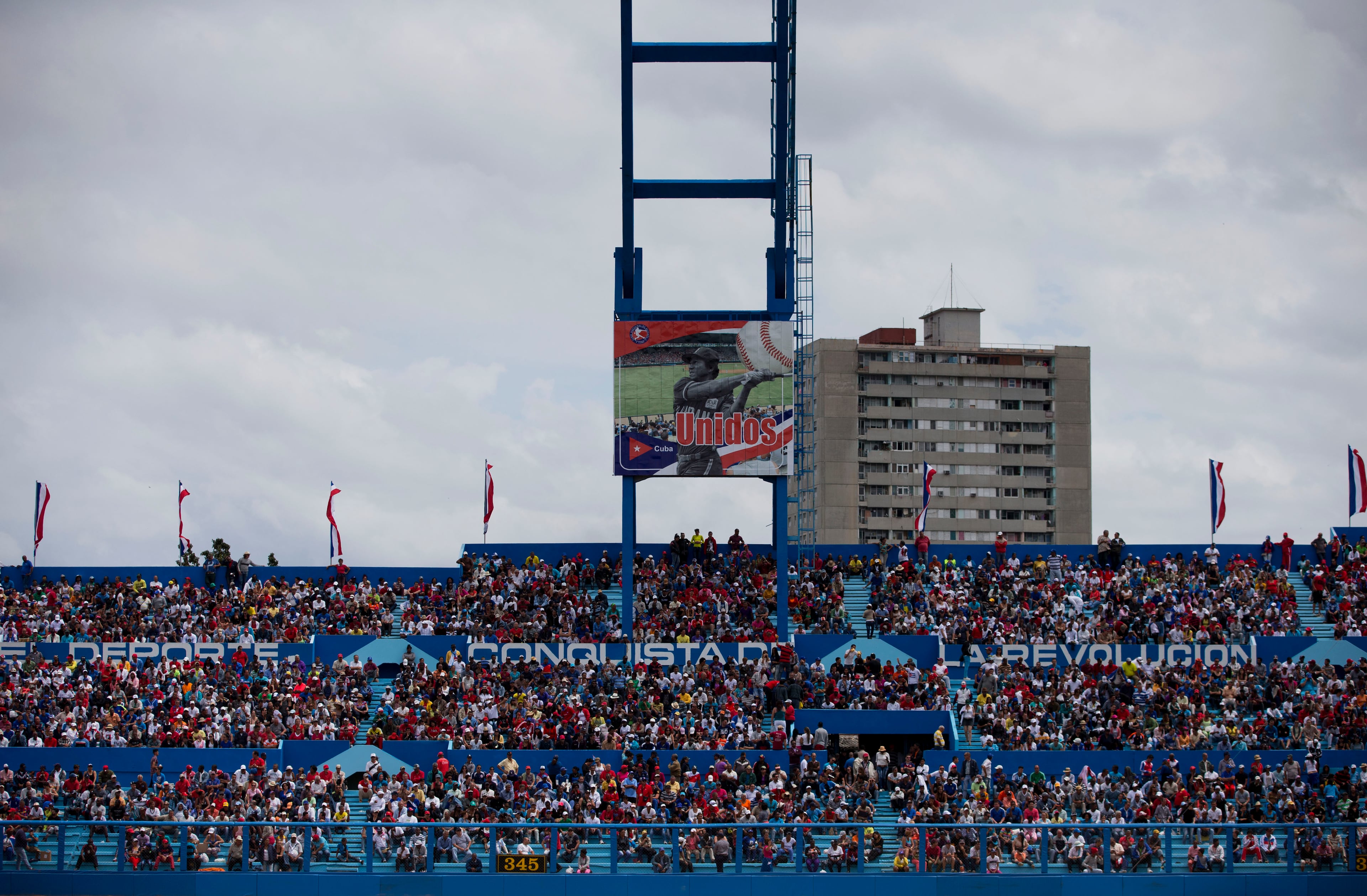 People sit in stands marked with the slogan, "Sport, a conquest of the revolution," as they await the start of the l game. (AP Photo/Rebecca Blackwell)