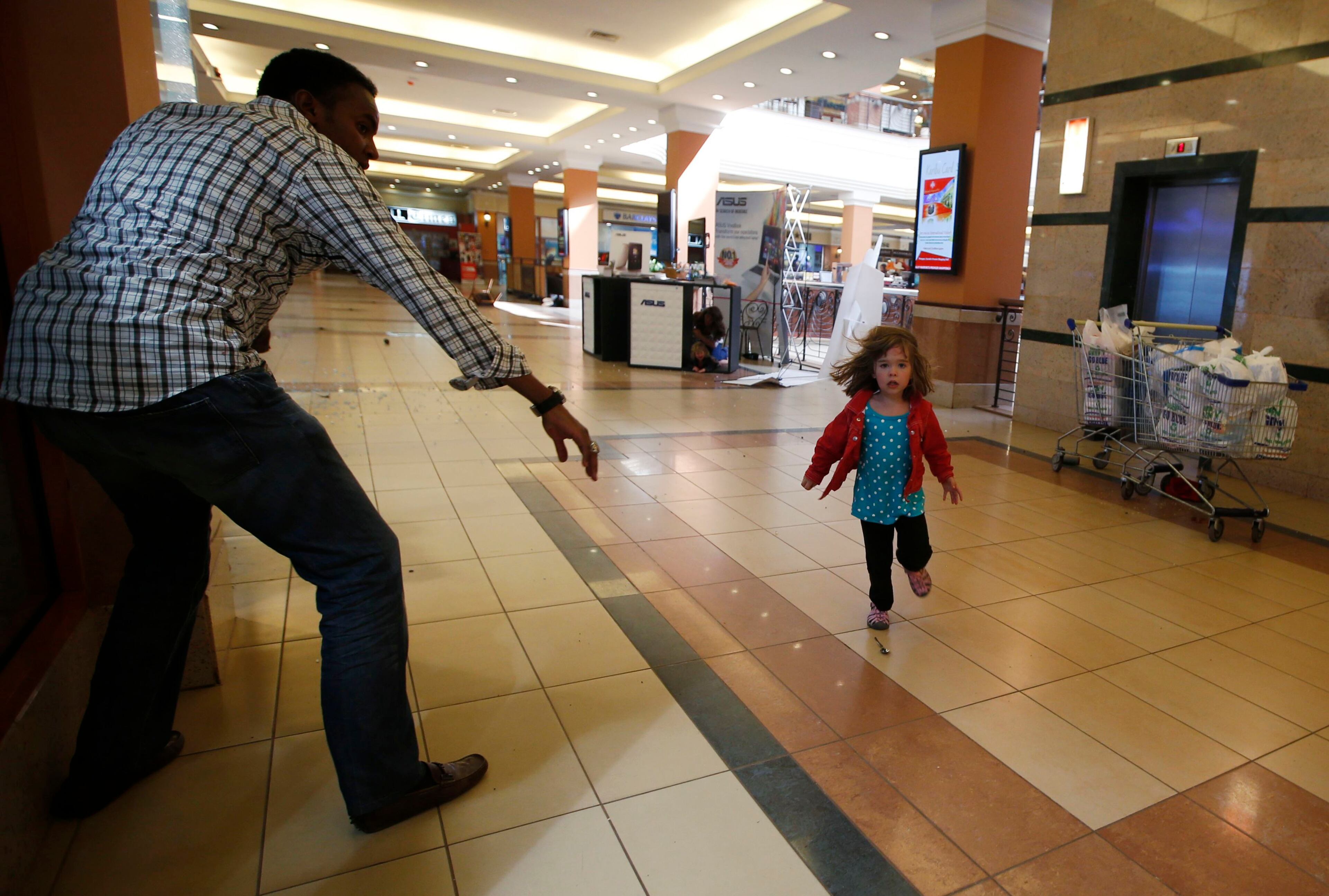 A child runs to safety as armed police hunt gunmen who went on a shooting spree at Westgate shopping centre in Nairobi September 21, 2013. The gunmen stormed a shopping mall in Nairobi killing at least 20 people in what Kenya's government said could be a terrorist attack, and sending scores fleeing into shops, a cinema and onto the streets in search of safety.