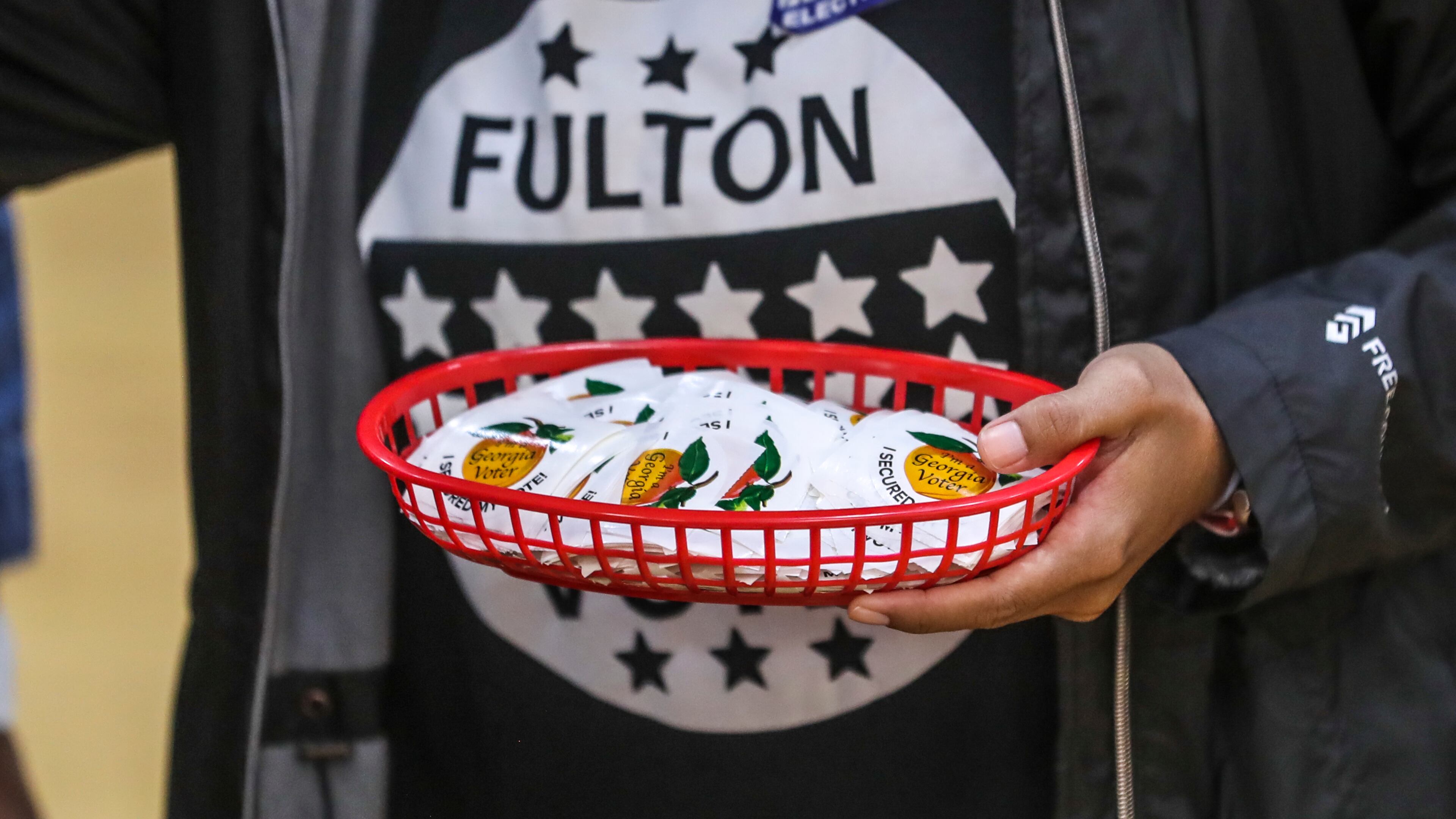 Poll worker, Wanda Davila holds stickers at the Dunbar Neighborhood Center on Election Day in November 2022. North Fulton cities eager to manage their own elections this November say they don’t have enough time to do so efficiently and will wait until 2025.
