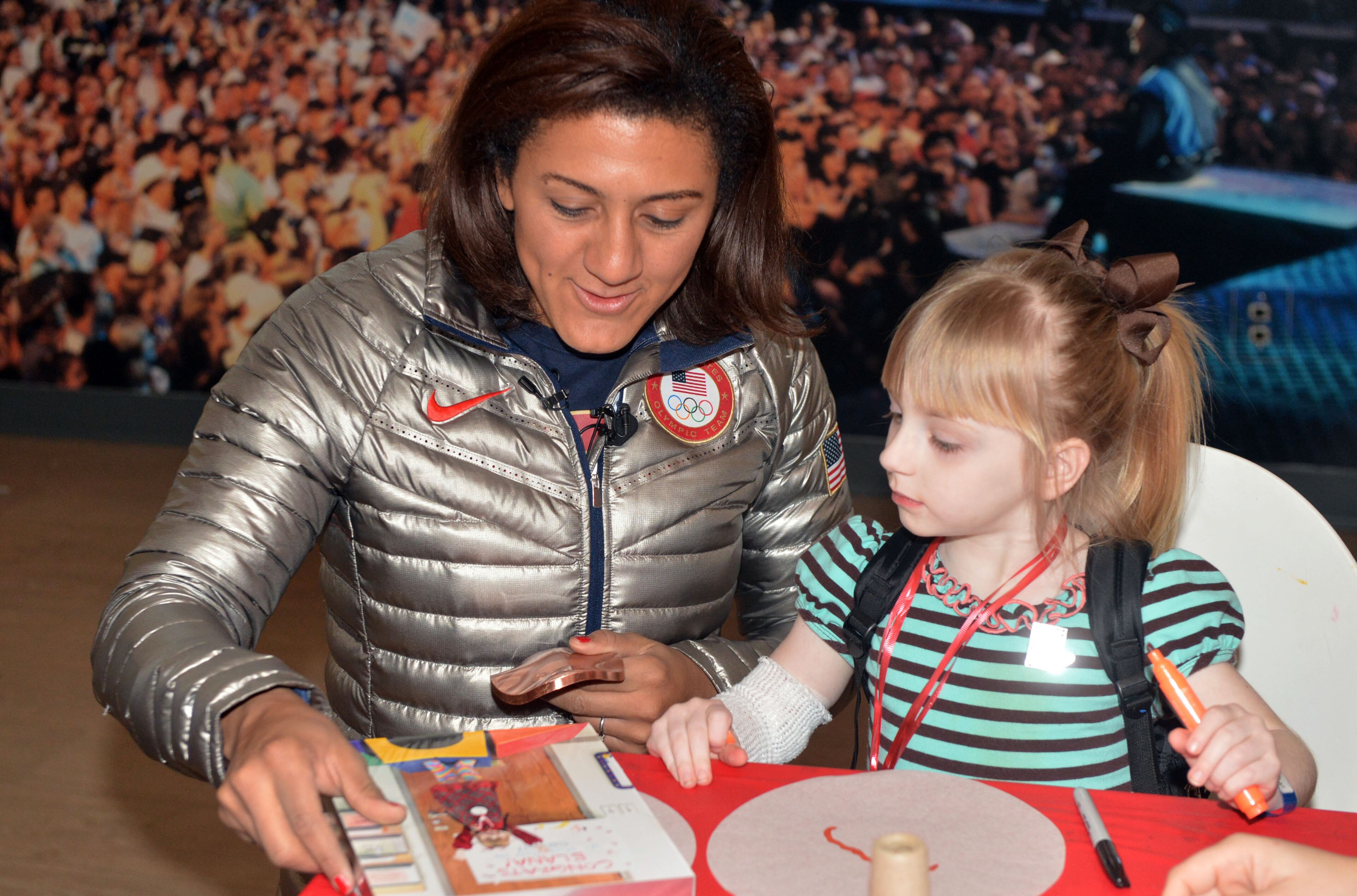 Douglasville-native Elana Meyers shares her silver medal from the Winter Olympic Games with Hanna Evans, 4, of Lawrenceville. KENT D. JOHNSON / KDJOHNSON@AJC.COM