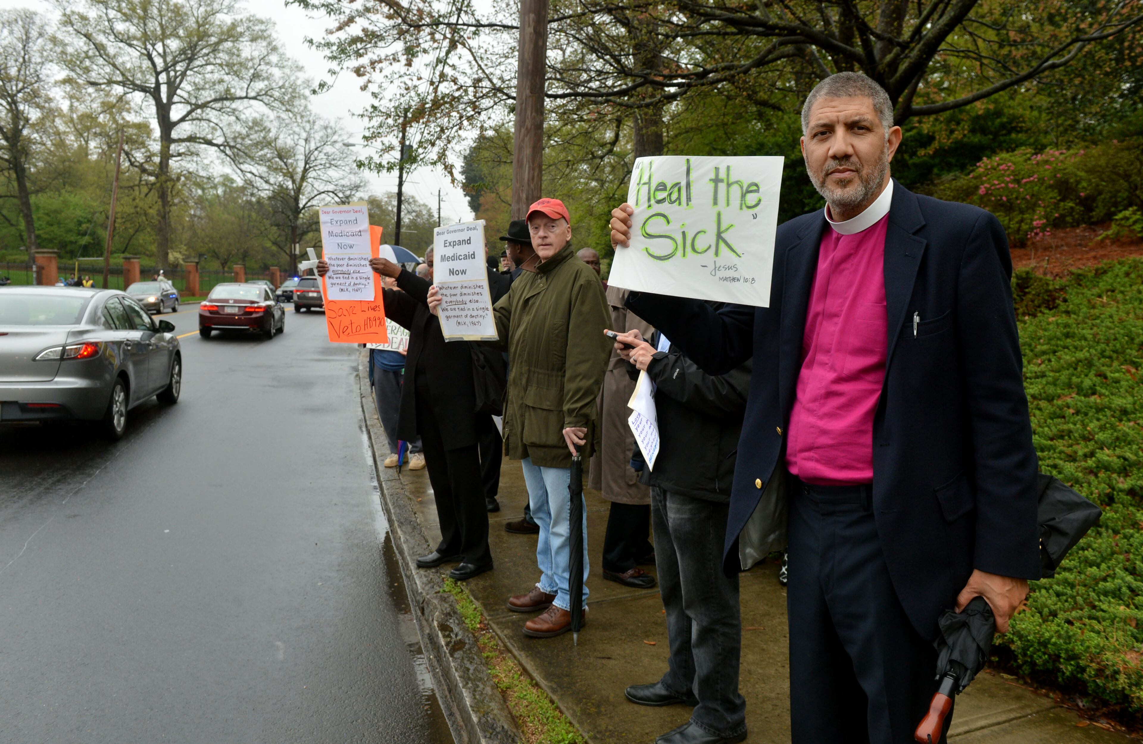 Episcopal Bishop Rob Wright joined with approximately 75 protesters, including several Atlanta clergy members, in a Medicaid expansion rally outside the Governor's Mansion on W. Paces Ferry Road Monday, April 7, 2014. Protesters were calling on Gov. Nathan Deal to expand Medicaid services in the state. KENT D. JOHNSON / KDJOHNSON@AJC.COM