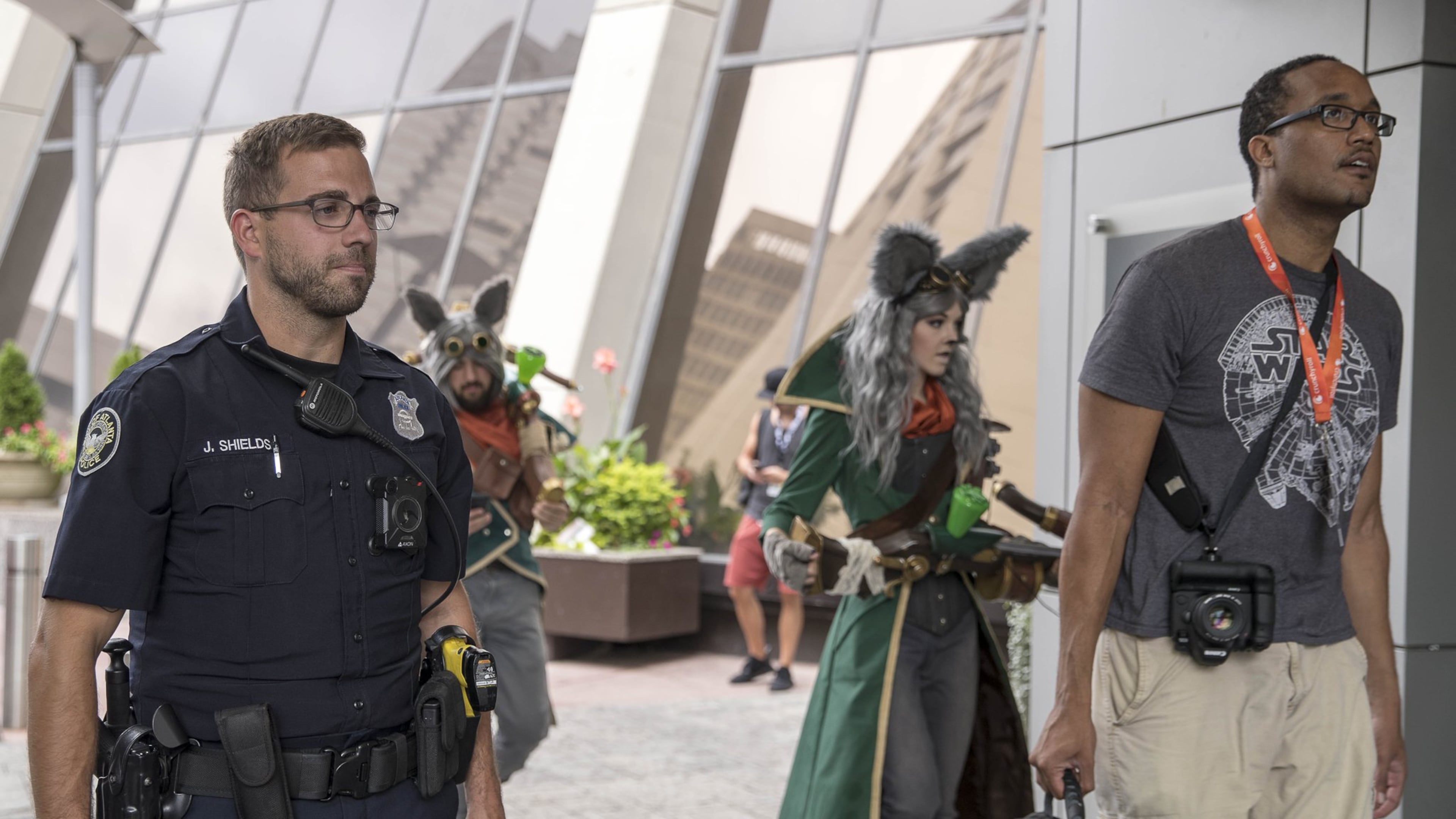 08/30/2018 — Atlanta, Georgia — Atlanta Police Officer Joshua Shields (left) surveys the outside of the Atlanta Hilton Hotel as DragonCon participants walk past. This is Shields’ third year over seeing the Hilton Hotel during DragonCon. (ALYSSA POINTER/ALYSSA.POINTER@AJC.COM)