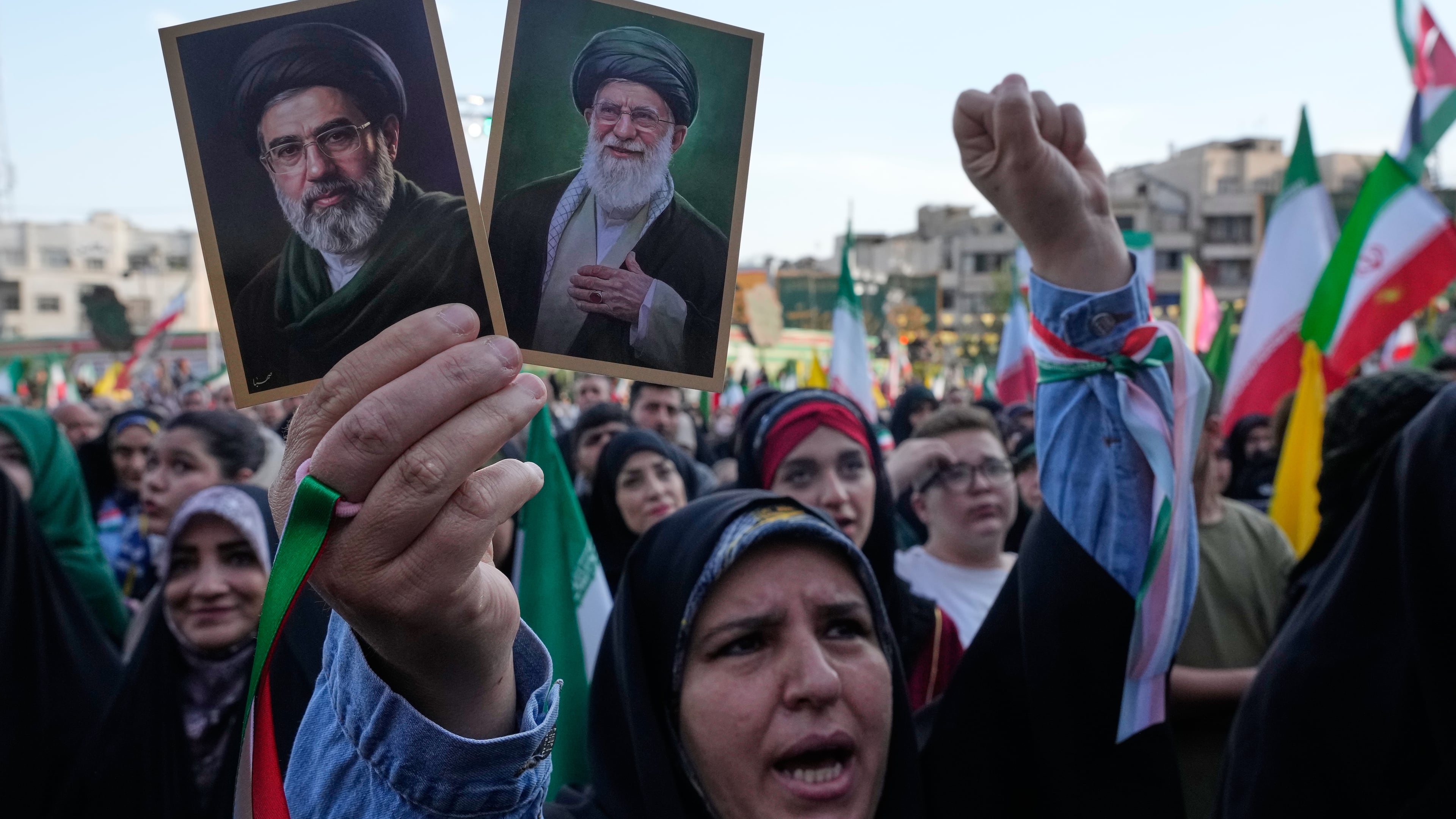 FILE - A woman holds up pictures of the Iranian Supreme Leader Ayatollah Mojtaba Khamenei, left, and his father, the slain Ayatollah Ali Khamenei, during a state-organized rally in Tehran, Iran, April 29, 2026. (AP Photo/Vahid Salemi, File)