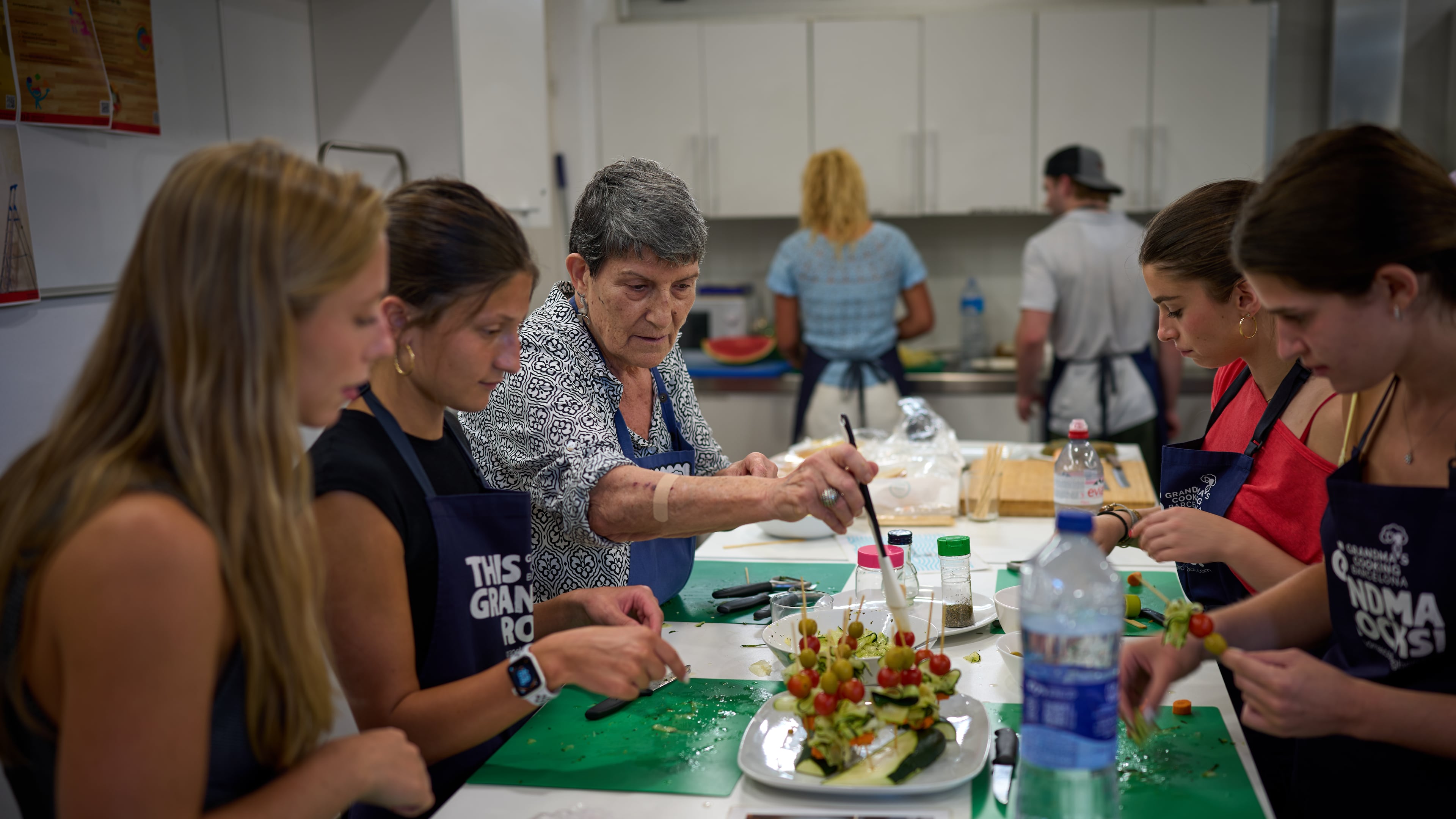 Nuria Isanda, 75, third from left, teaches tourists how to prepare and present traditional Spanish dishes during a cooking workshop at Grandmas Cooking in Barcelona, Spain, Wednesday, Oct. 14, 2026. (AP Photo/Emilio Morenatti)