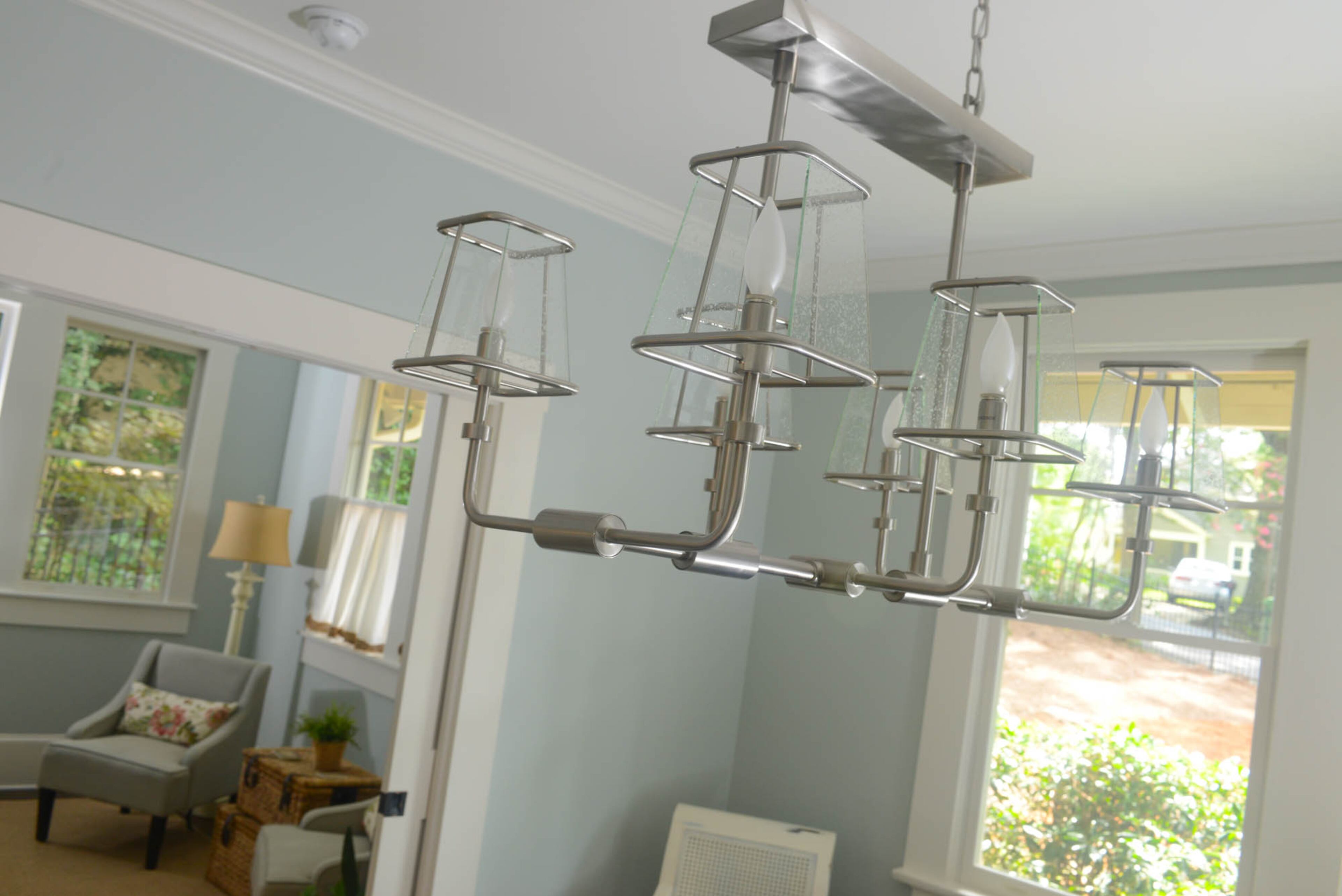 A striking six-light chandelier in satin nickel, from Savoy House’s Damascus collection, hangs above the dining room table.