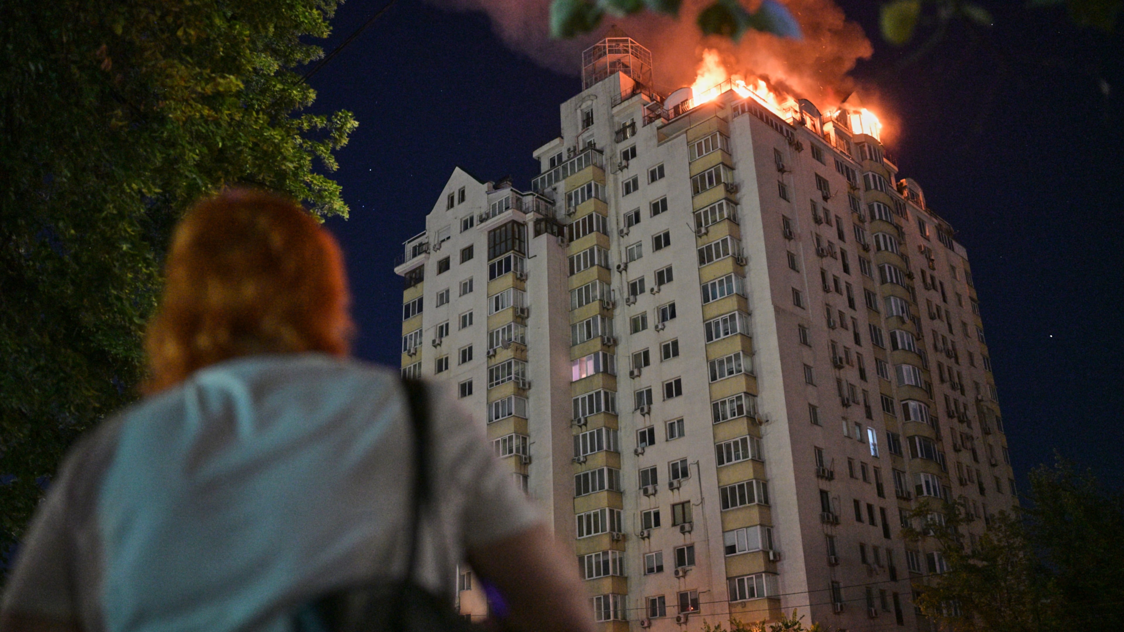 A woman looks at an apartment building burning after a Russian missile attack in Kyiv, Ukraine, Thursday, July 2, 2026. (AP Photo/Danylo Antoniuk)