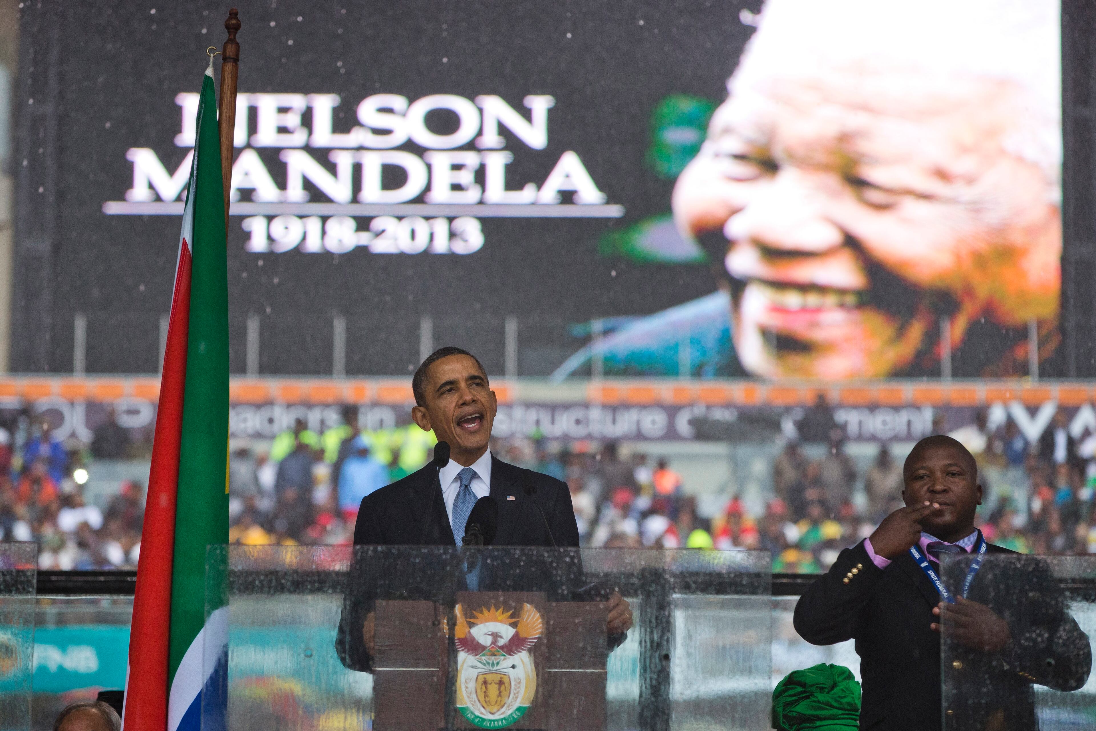 President Barack Obama delivers his speech next to a sign language interpreter during a memorial service at FNB Stadium in honor of Nelson Mandela on Tuesday, Dec. 10, 2013 in Soweto, near Johannesburg. The national director of the Deaf Federation of South Africa says a man who provided sign language interpretation on stage for Nelson Mandela's memorial service in a soccer stadium was a fake.