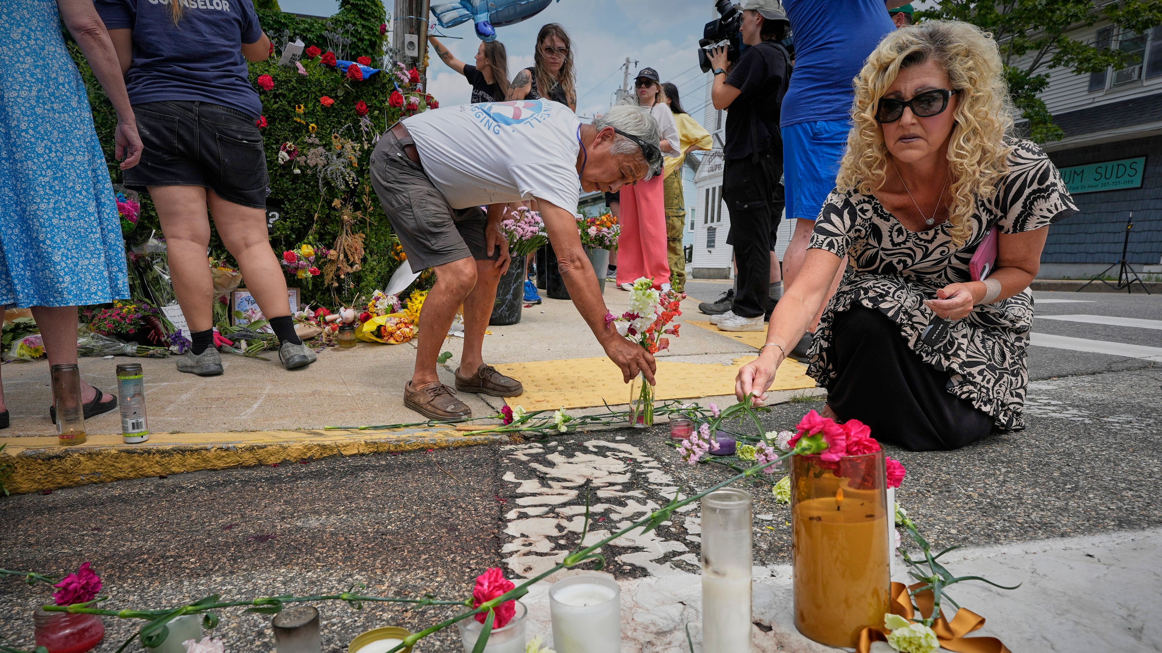 Mourners place flowers and candles in Biddeford, Maine, Wednesday, July 15 2026, near the blood-stained pavement where Johan Sebastián Durán Guerrero was pulled from his car on Monday by U.S. Immigration and Customs Enforcement agents. (AP Photo/Robert F. Bukaty)