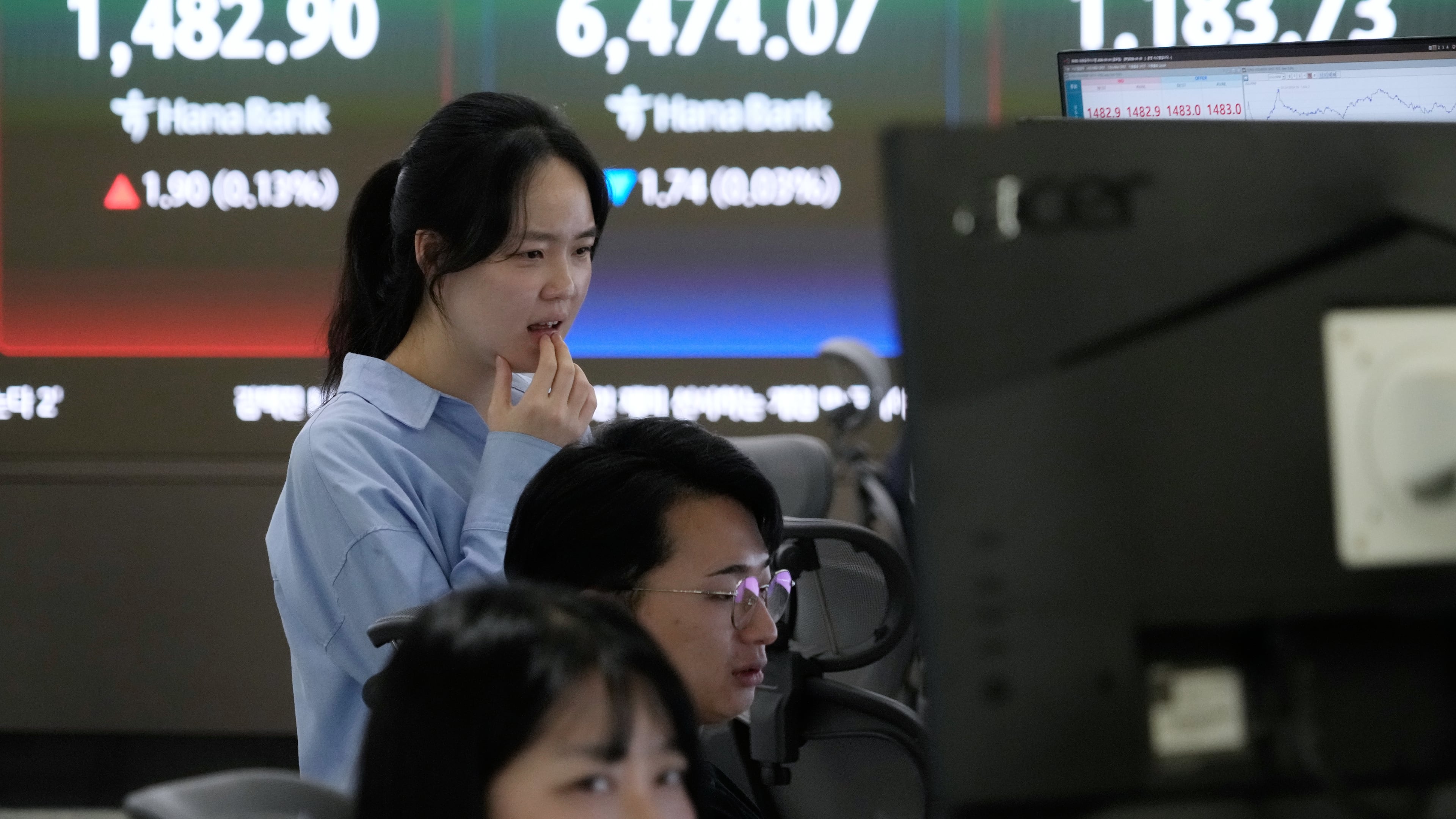 A currency trader watches monitors near a screen showing the Korea Composite Stock Price Index (KOSPI), top center, and the foreign exchange rate between U.S. dollar and South Korean won, top center left, at the foreign exchange dealing room of the Hana Bank headquarters in Seoul, South Korea, Friday, April 24, 2026. (AP Photo/Ahn Young-joon)