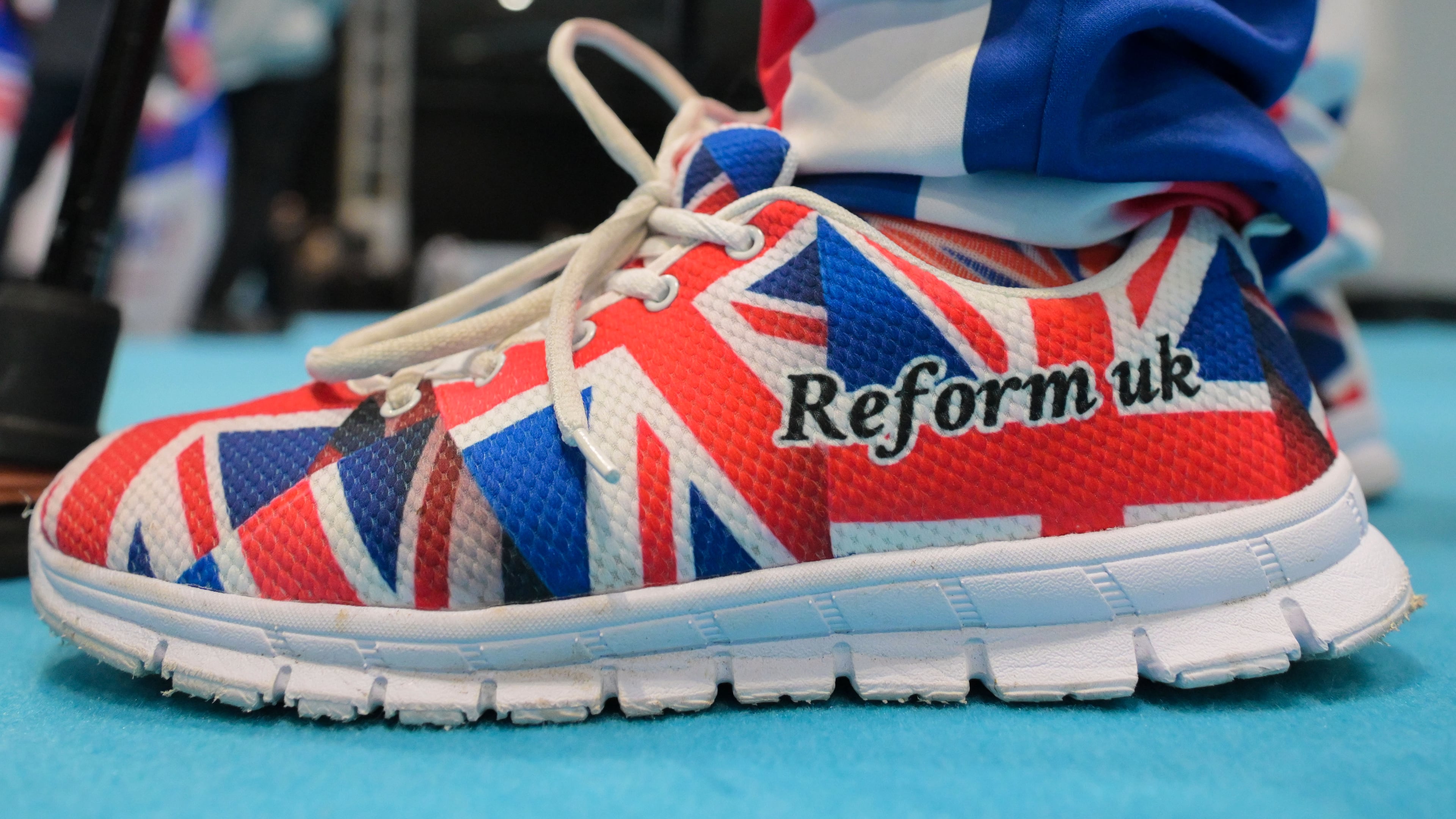 A member wears shoes in Union Flag colours during the Reform party's annual conference at the National Exhibition Centre in Birmingham, England, Friday, Sept. 4, 2026. (AP Photo/Thomas Krych)