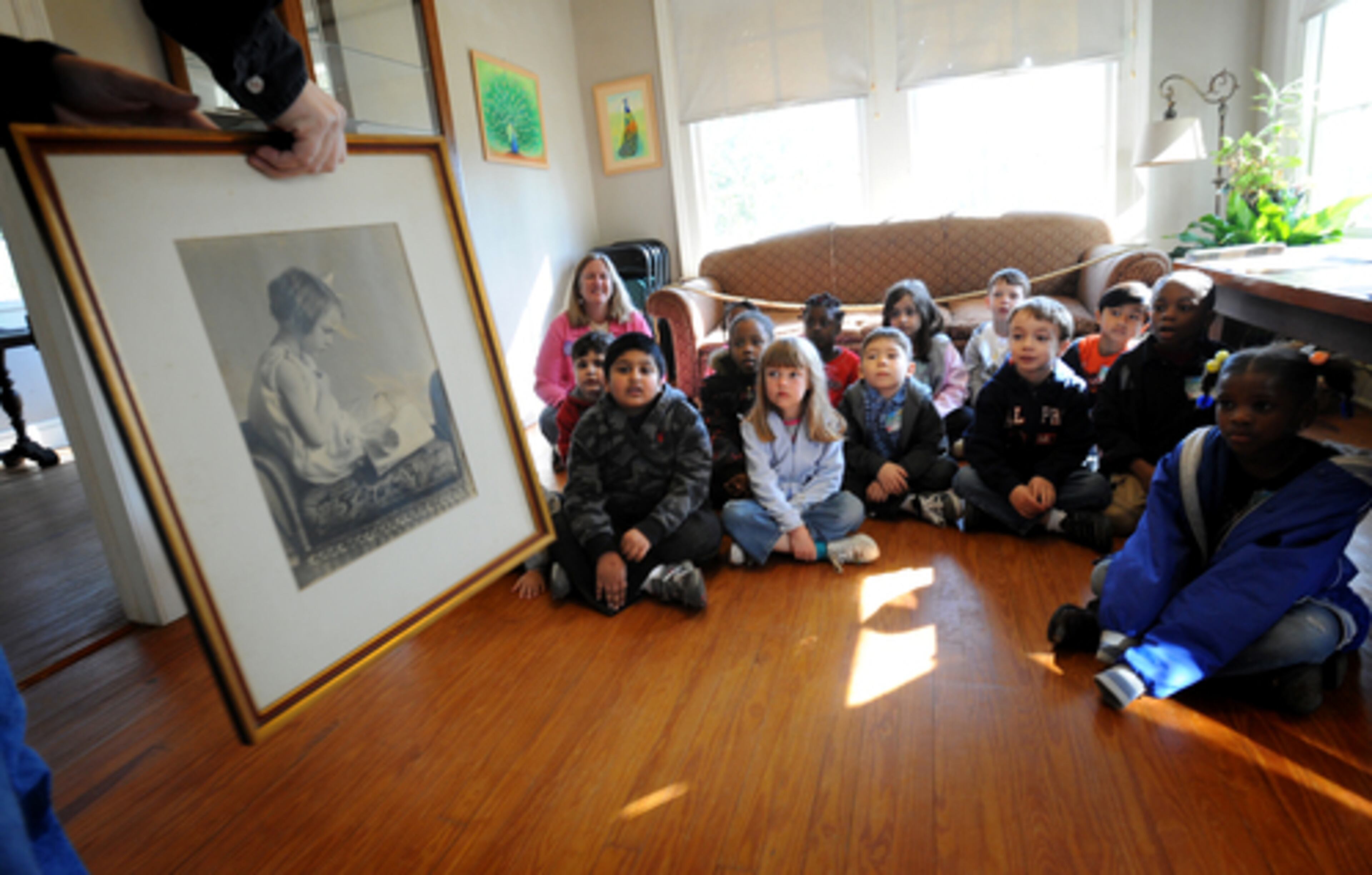 Executive Director Craig Amason holds a picture of O'Connor reading a book to show to kindergarten students at the museum during the tour.