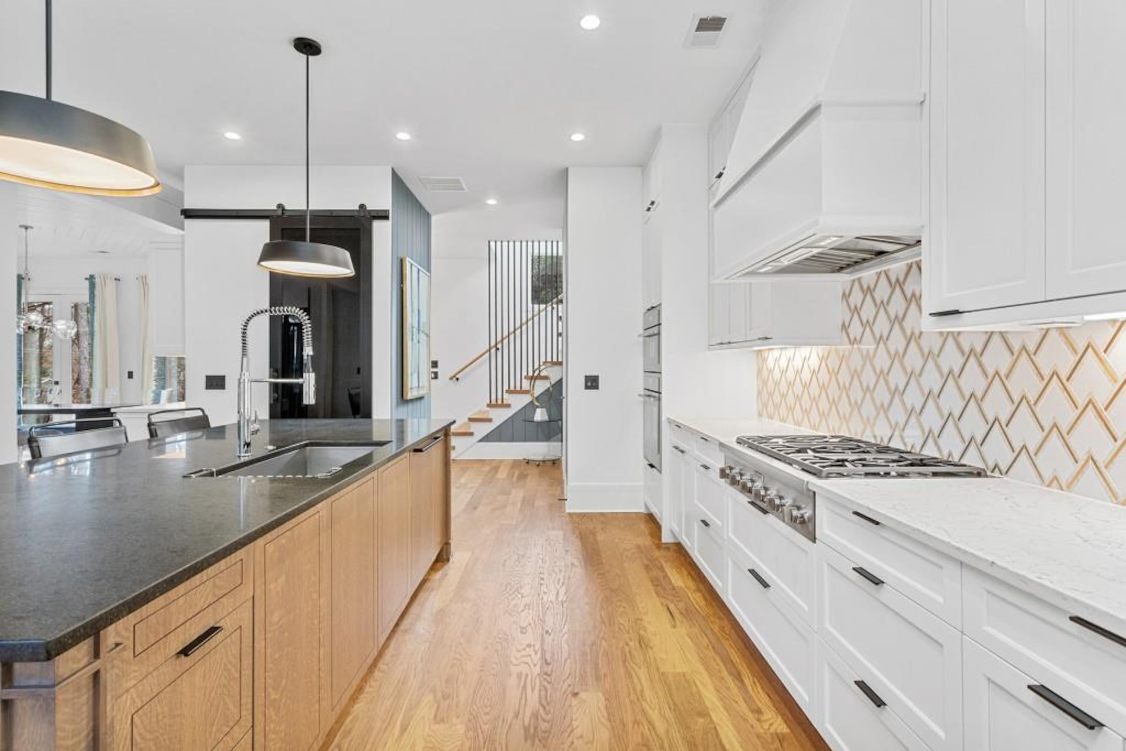 Chef's kitchen featuring oversized island with honed quartzite countertops, commercial grade stainless steel appliance package, custom backsplash, walk-in pantry and an abundance of storage space.