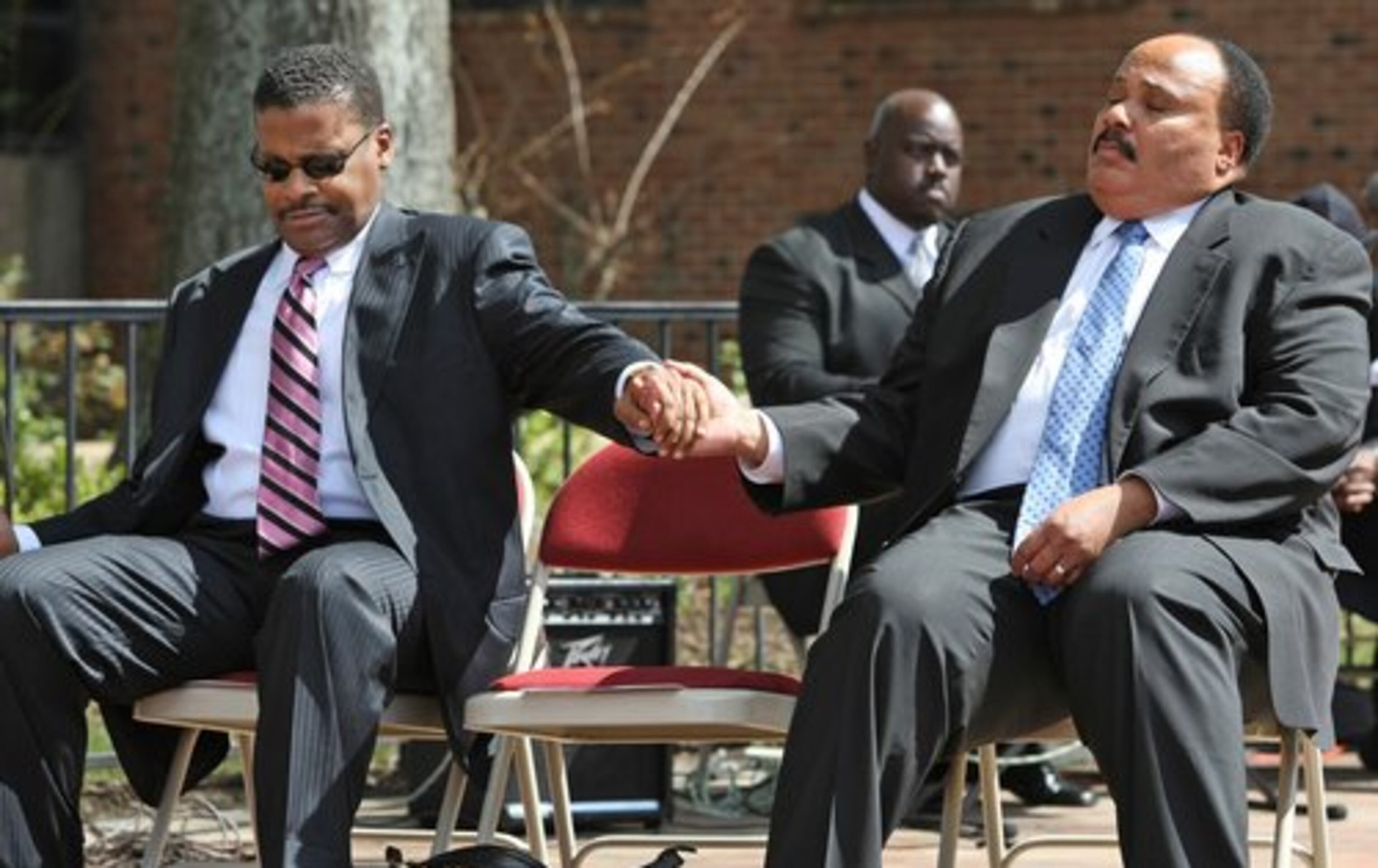 Isaac Newton Farris Jr. (left), president and CEO of the King Center, holds hands with his first cousin, Martin Luther King III during a prayer.