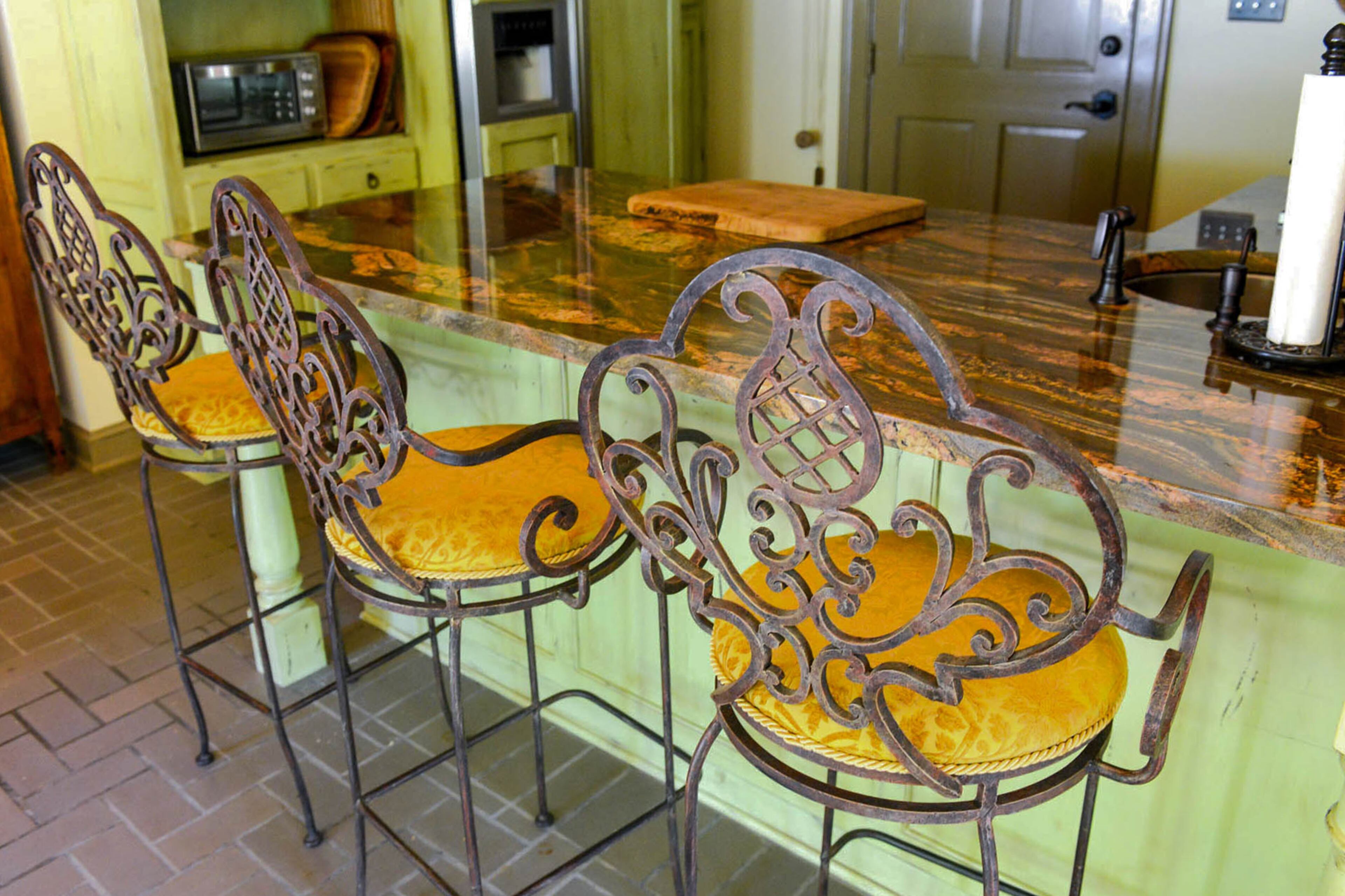 A trio of bar chairs pull up to the granite countertop in the kitchen of the pool house.