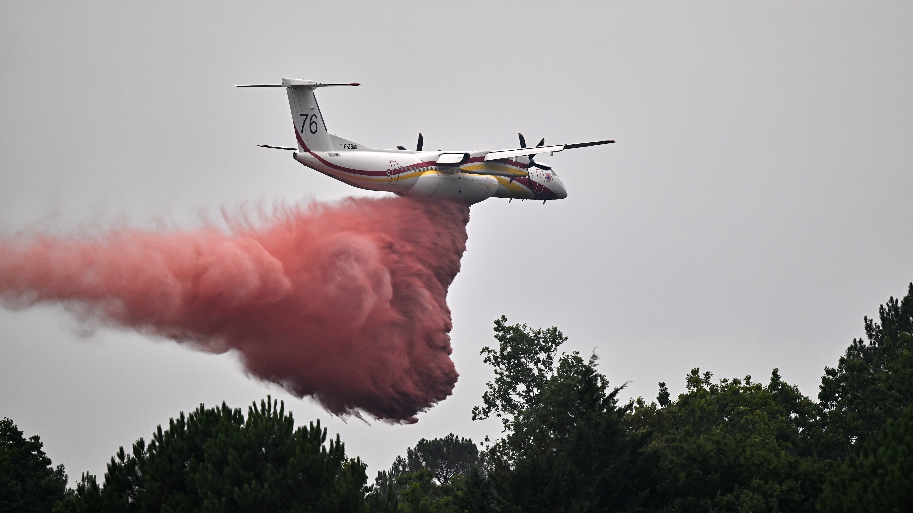 A De Havilland Canada DHC-8-400 Dash 8 operated by the French civil defense agency drops fire retardant as wildfires rage near Marcheprime, outside Bordeaux, France, Monday, July 27, 2026. (AP Photo/Emma Da Silva)