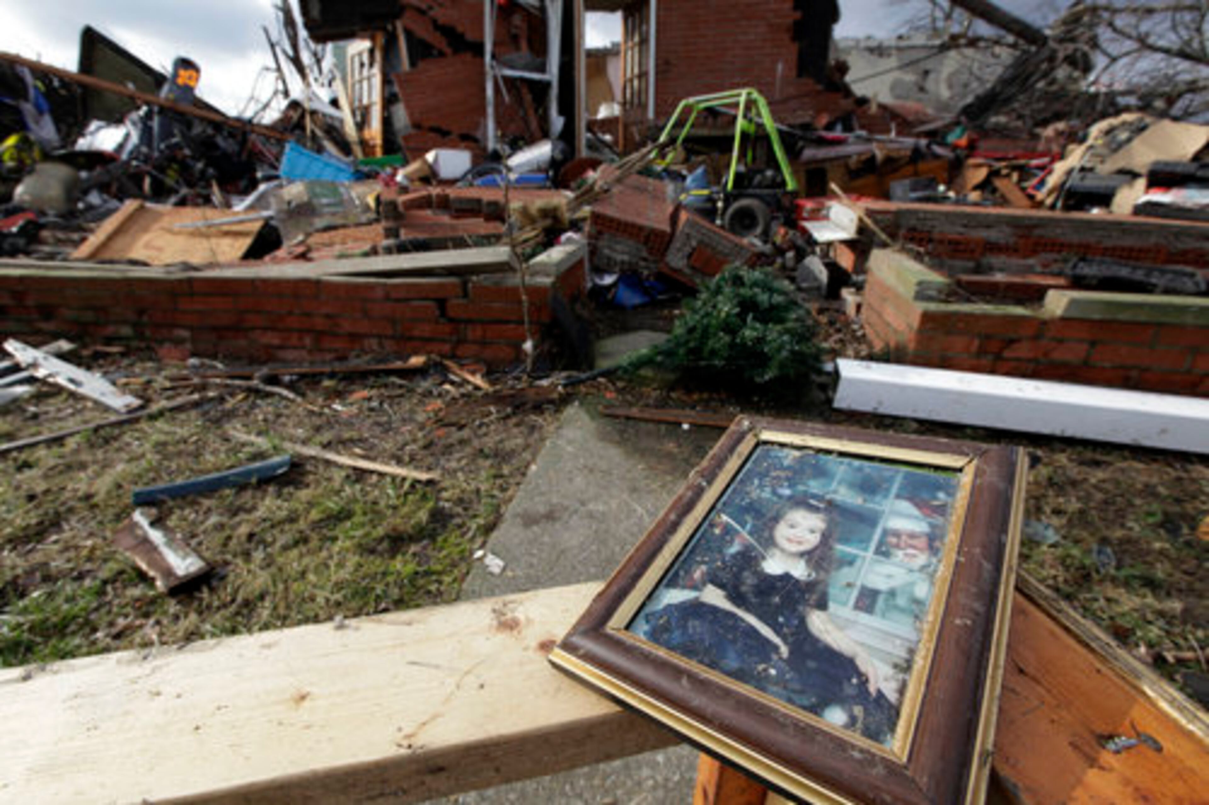 A photo and other remains scatter in front of a damaged house in Marysville, Ind., Saturday, March 3, 2012. Massive thunderstorms, predicted by forecasters for days, threw off dozens of tornadoes as they raced Friday from the Gulf Coast to the Great Lakes. Twisters crushed blocks of homes, knocked out cellphones and landlines, ripped power lines from broken poles and tossed cars, school buses and tractor-trailers onto roads made impassable by debris.