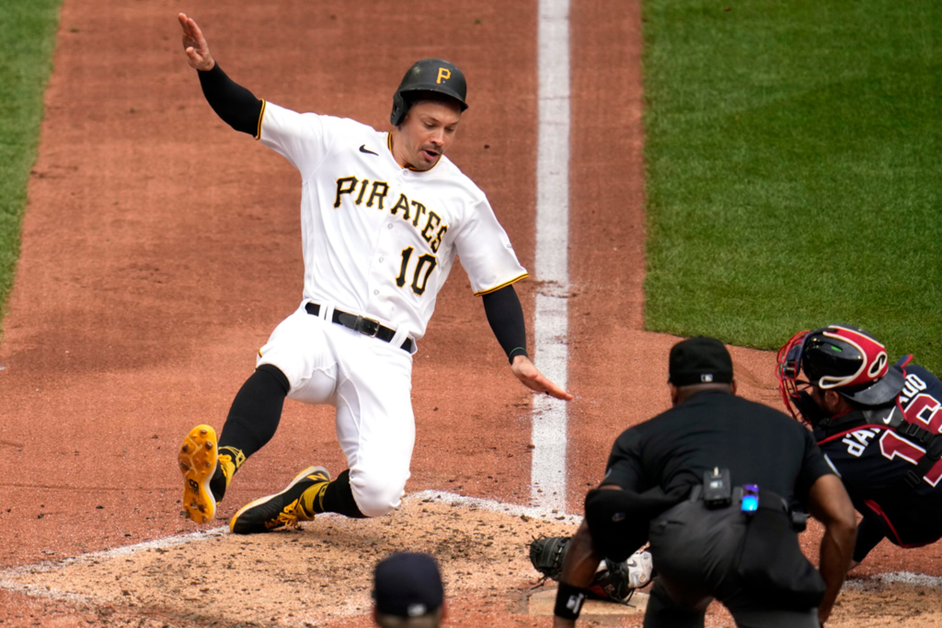 Pittsburgh Pirates' Bryan Reynolds (10) scores past Atlanta Braves catcher Travis d'Arnaud, obscured behind umpire Alan Porter, right, on a sacrifice fly by Alonso Rivas during the third inning of a baseball game in Pittsburgh, Thursday, Aug. 10, 2023. (AP Photo/Gene J. Puskar)