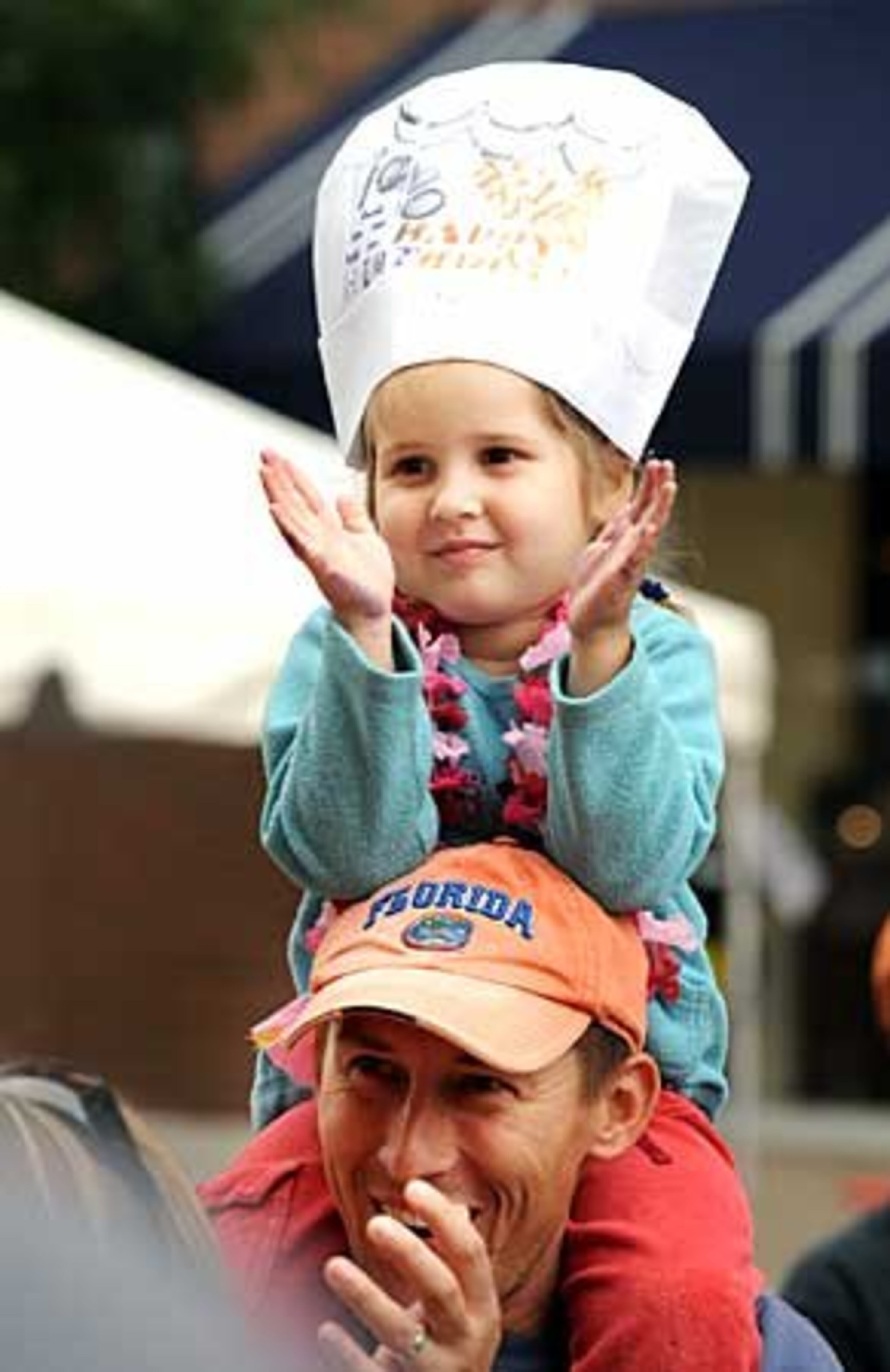 Kyara Dzenis, 4, of Sharpsburg, Ga., gives a round of applause for chef George Duran while sitting atop the shoulders of her father, Gunars Dzeni. Duran gave a demonstration of pizza fondue and roasted brussel sprouts on Kid's Avenue.