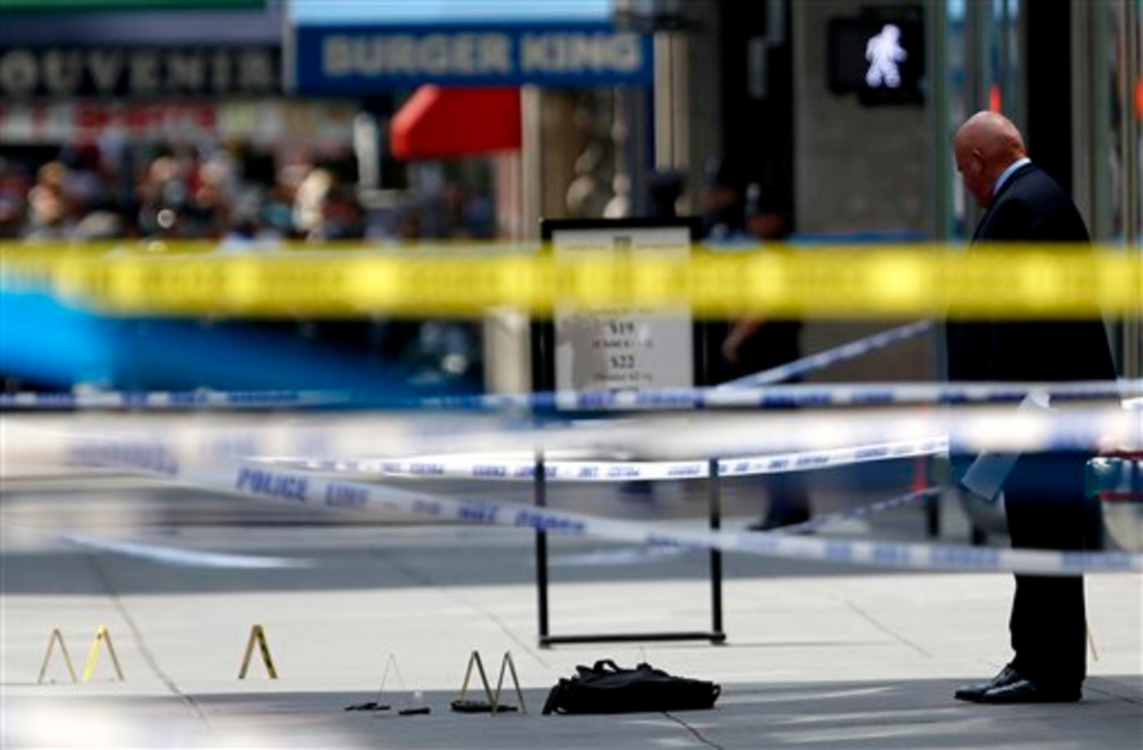 An official inspects evidence near the Empire State Building following a shooting, Friday, Aug. 24, 2012, in New York. New York City Mayor Michael Bloomberg said some of the victims may have been hit by police bullets as police and the gunman exchanged fire. Police say a recently laid-off worker shot a former colleague to death near the iconic skyscraper and then randomly opened fired on people nearby before firing on police. (AP Photo/Julio Cortez)